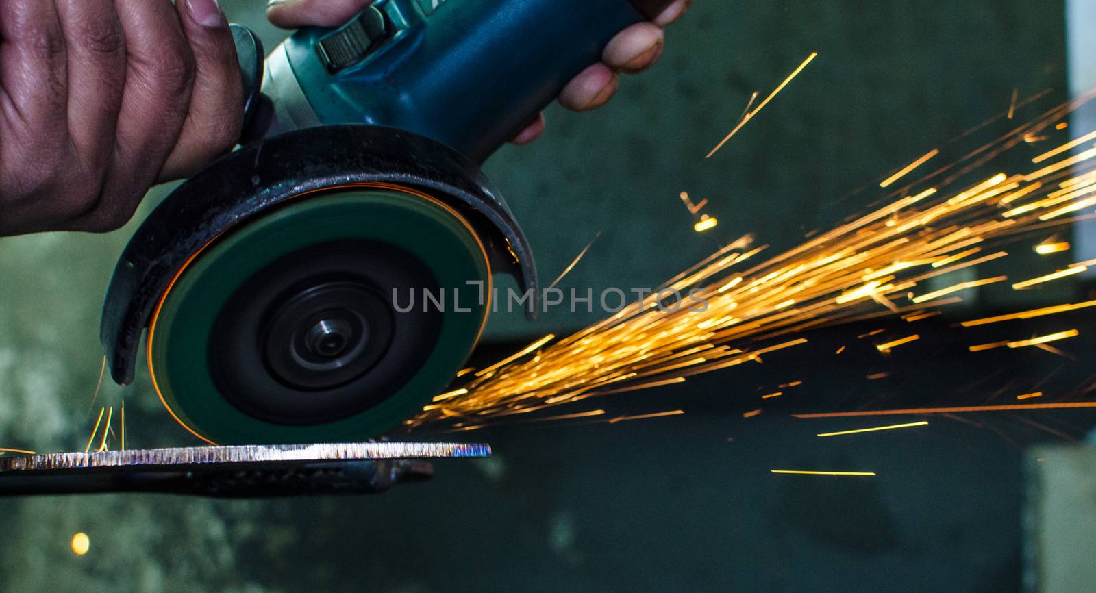 Industrial grinder showers sparks while working with metal.