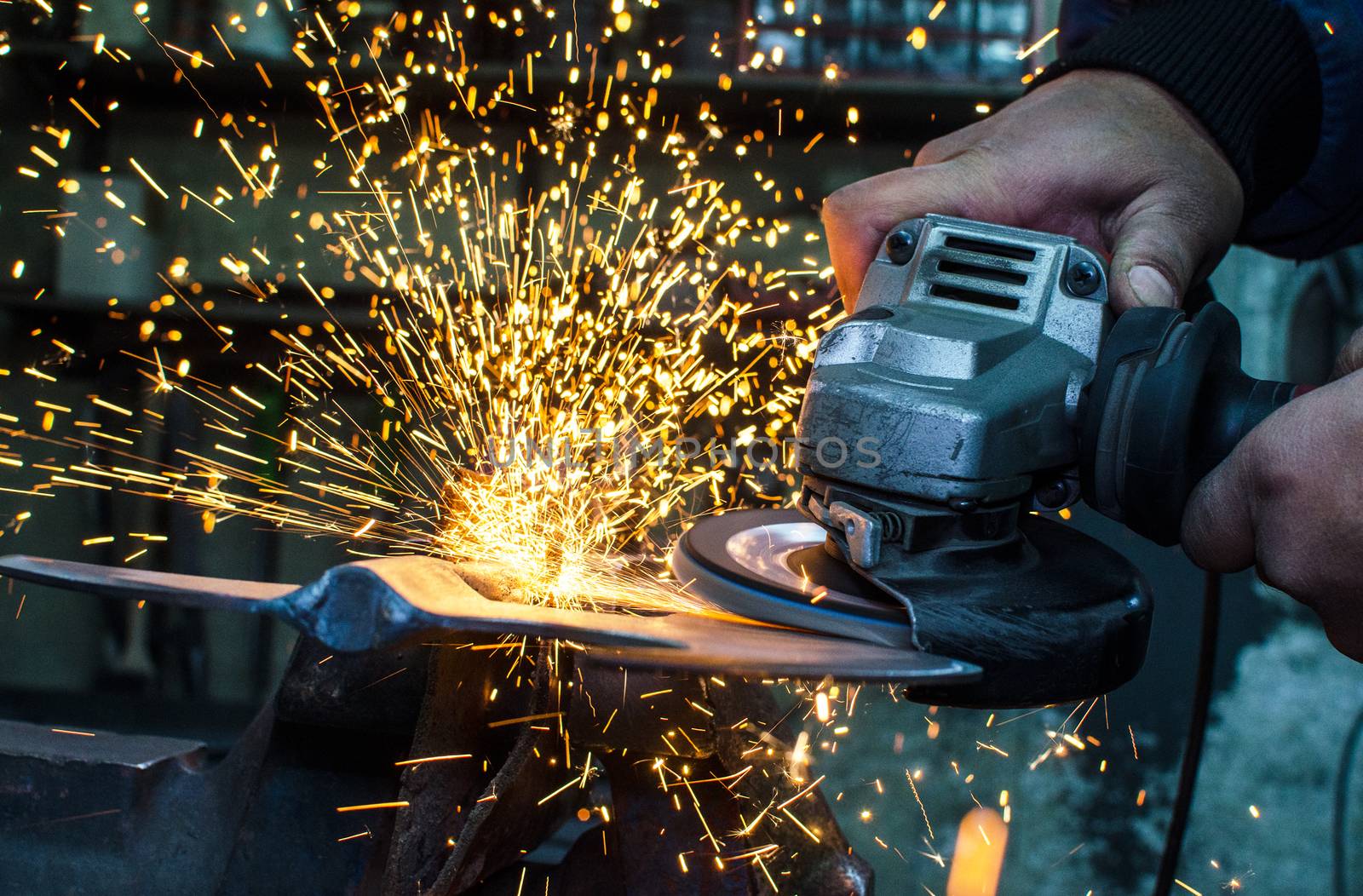 Industrial grinder showers sparks while working with metal.