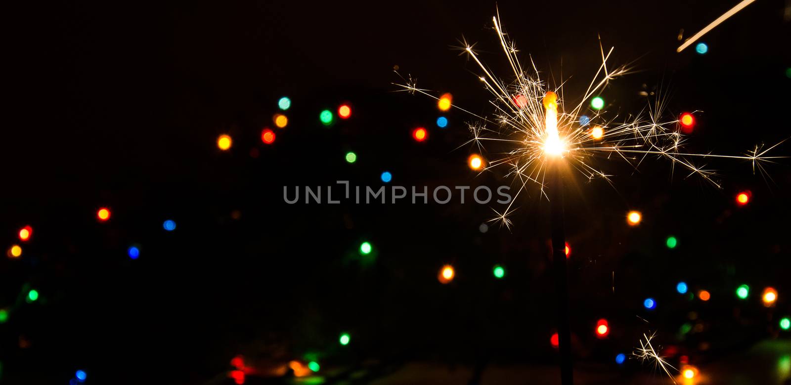 Sparkler and Christmas lights. by noskaphoto