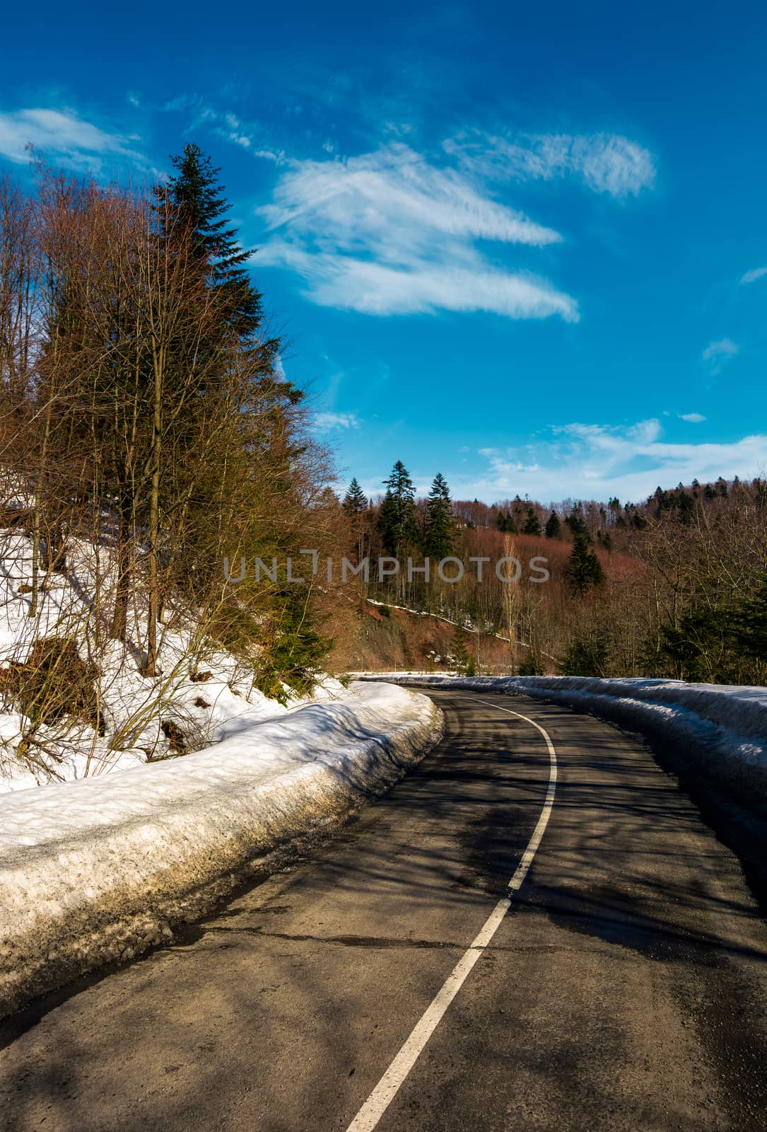 turnaround on the mountain road in winter. forested hills with snow on roadside under the clear blue sky