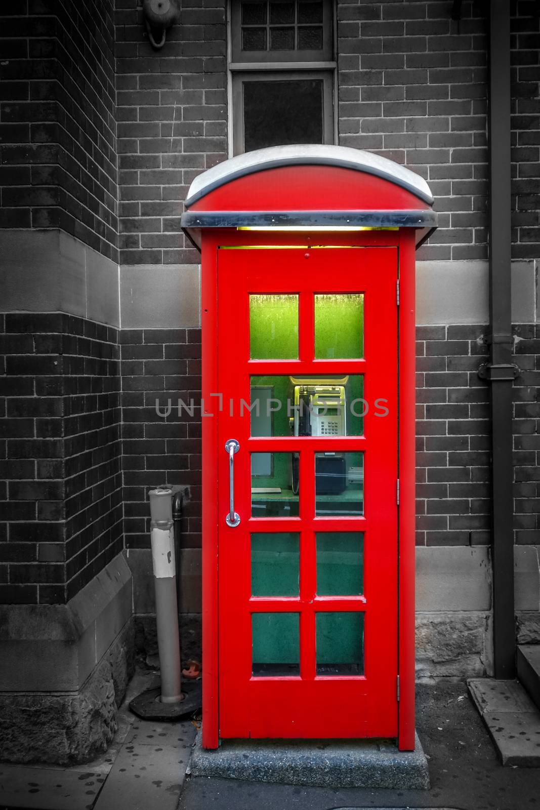 Vintage UK red phone booth in front of a brick wall