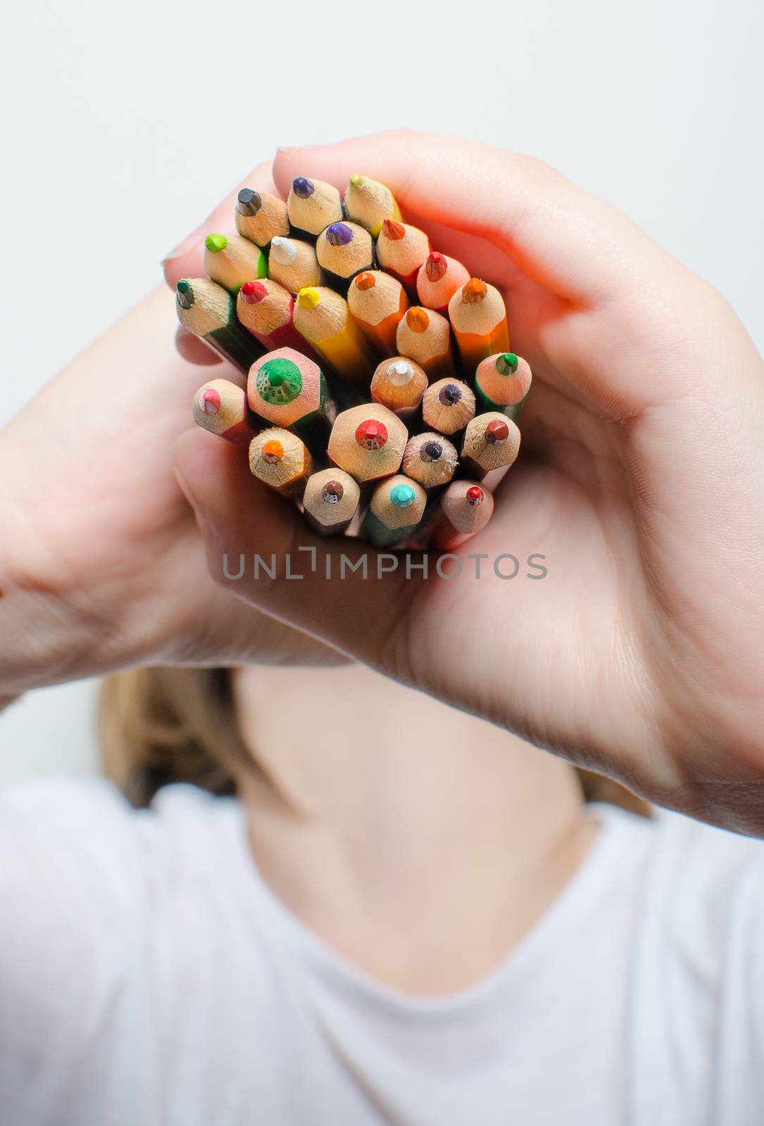Colored pencils for painting in children's hands on a white background.