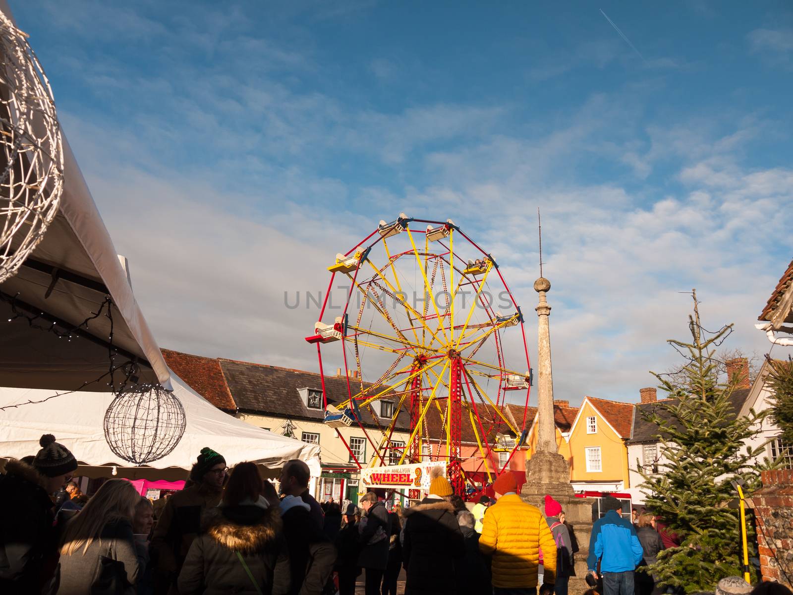red and yellow carousel wheel outside with people below blue sky christmas fair; essex; england; uk