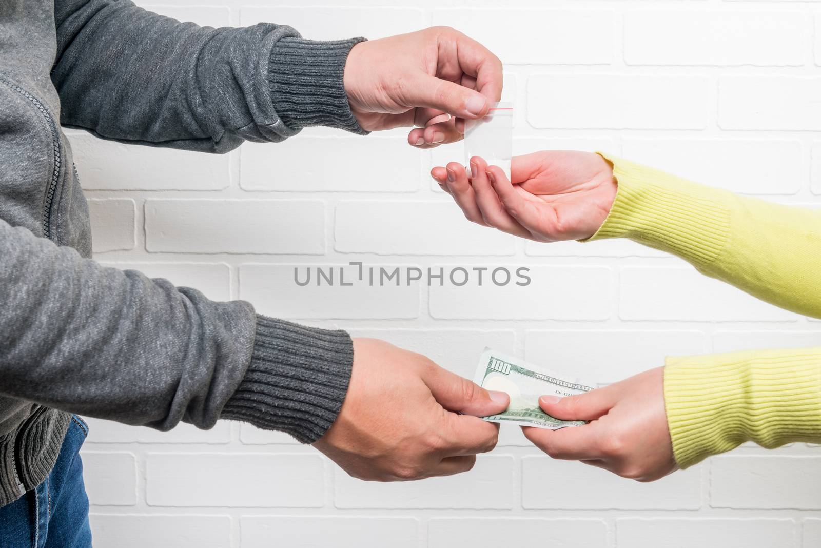 Man sells a woman a dose of drugs against a brick wall background