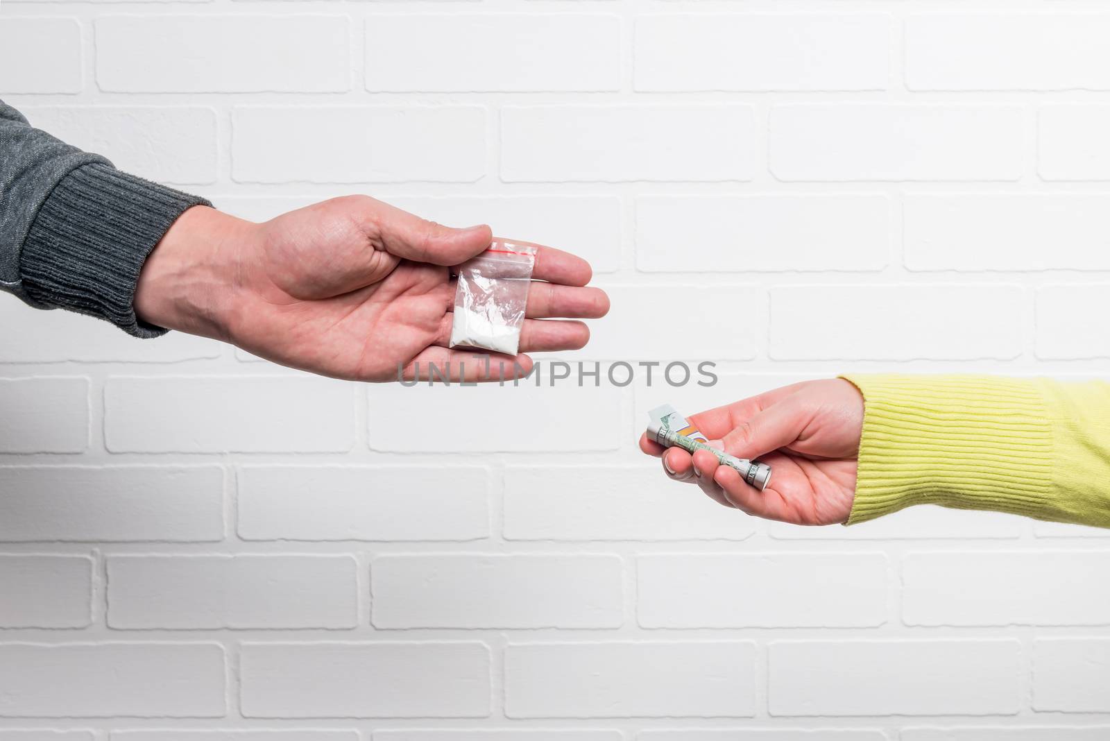 Transfer of money and drugs close-up against a white brick wall by kosmsos111