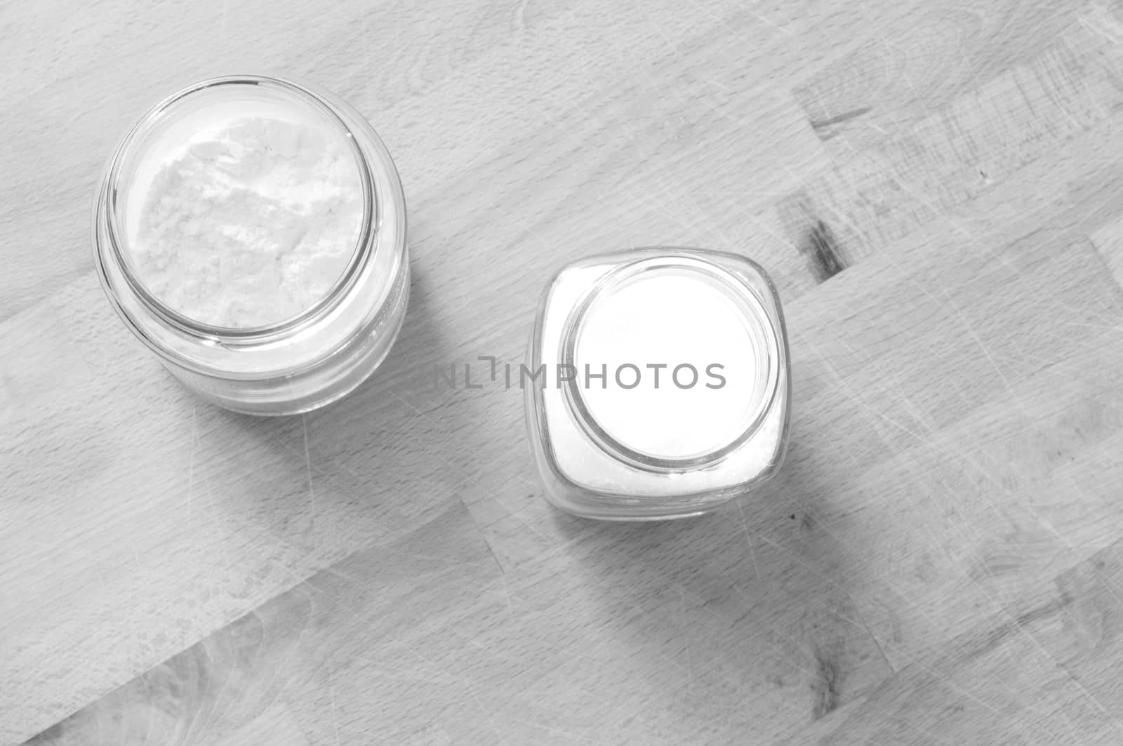 two glass jars raised from above with sugar and flour on the wooden kitchen table