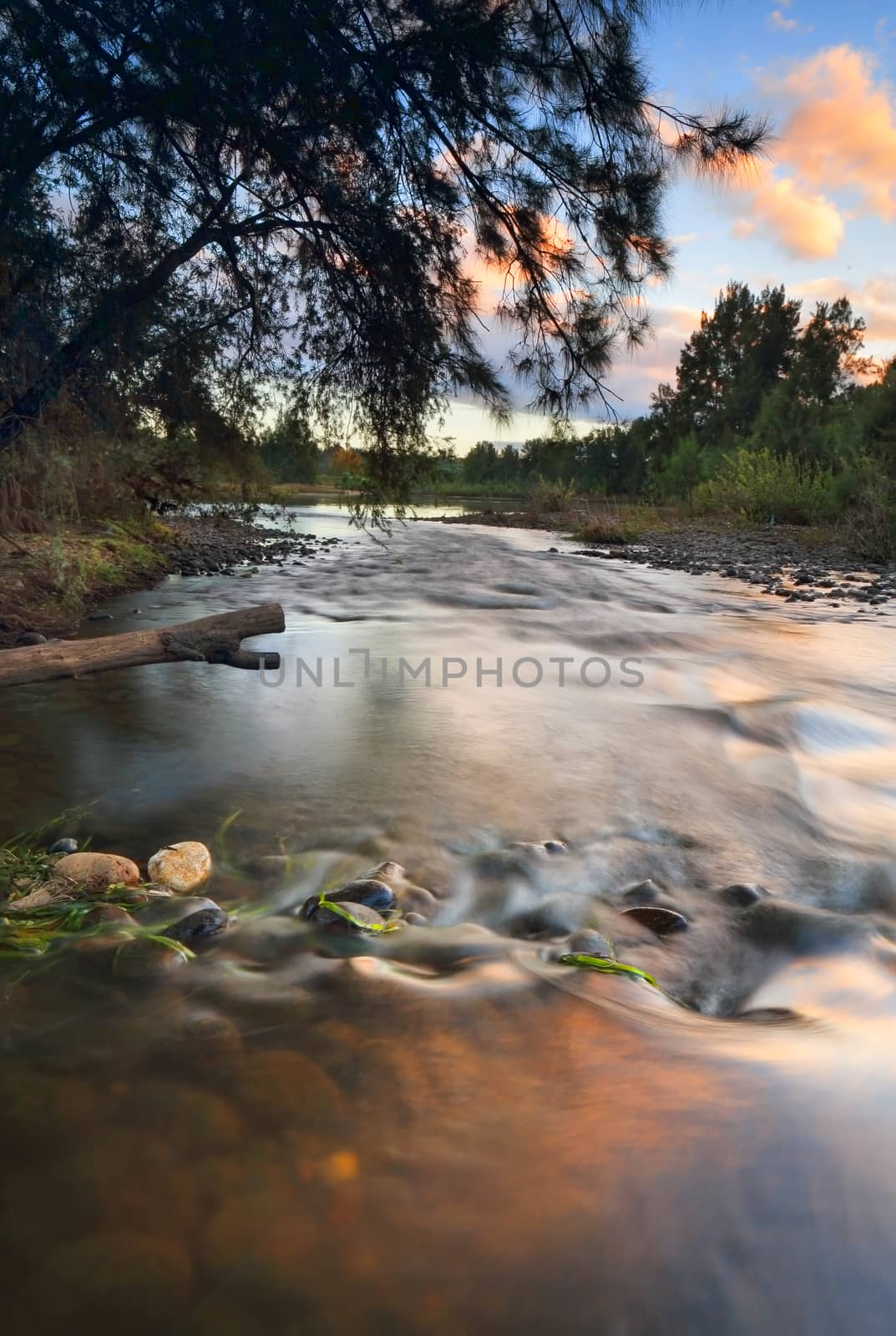 Water flowing over a stony river bed with sunrise reflections.  Nepean River Yarramundi