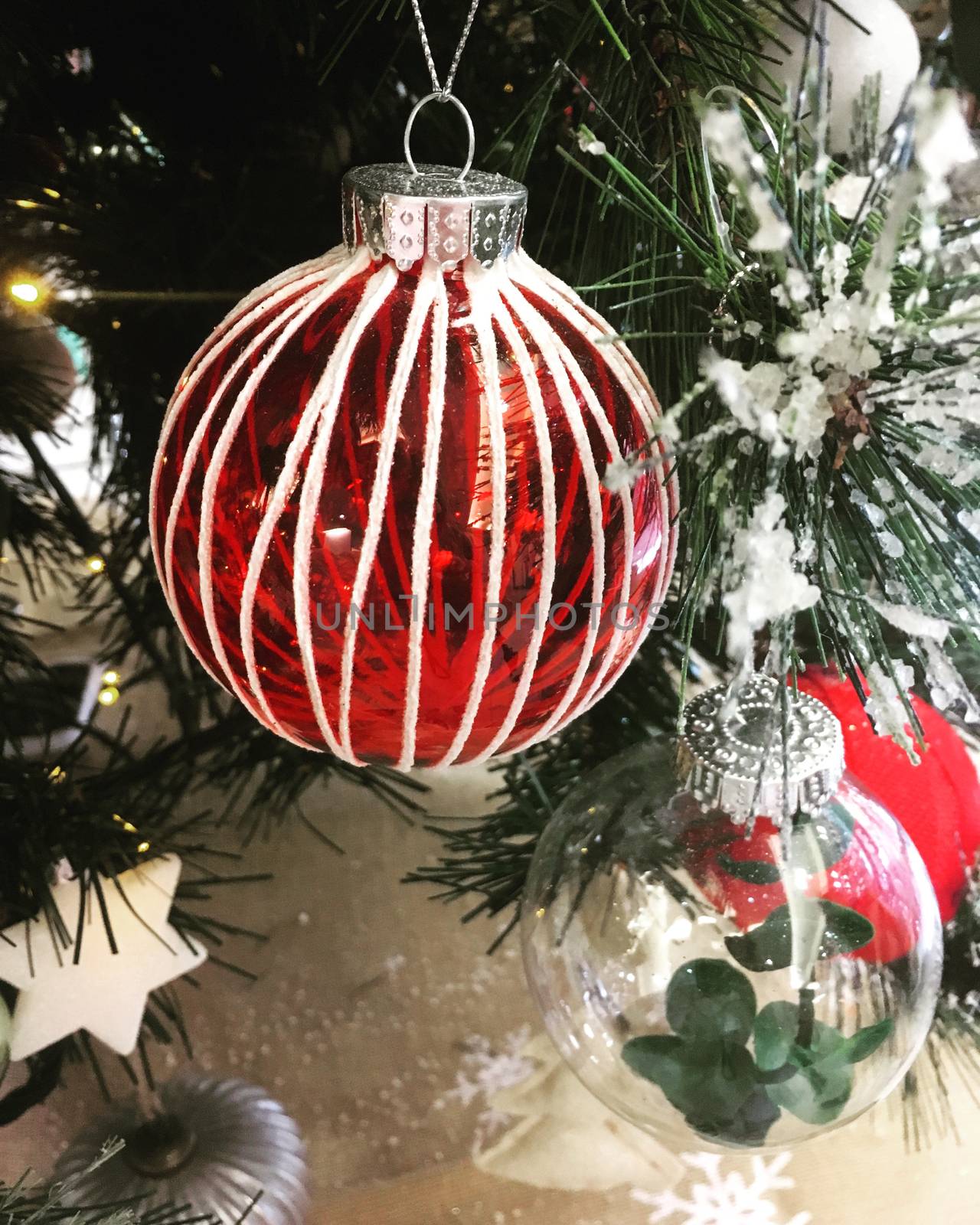 Christmas baubles and other seasonal decorations hang on a snowy Christmas tree