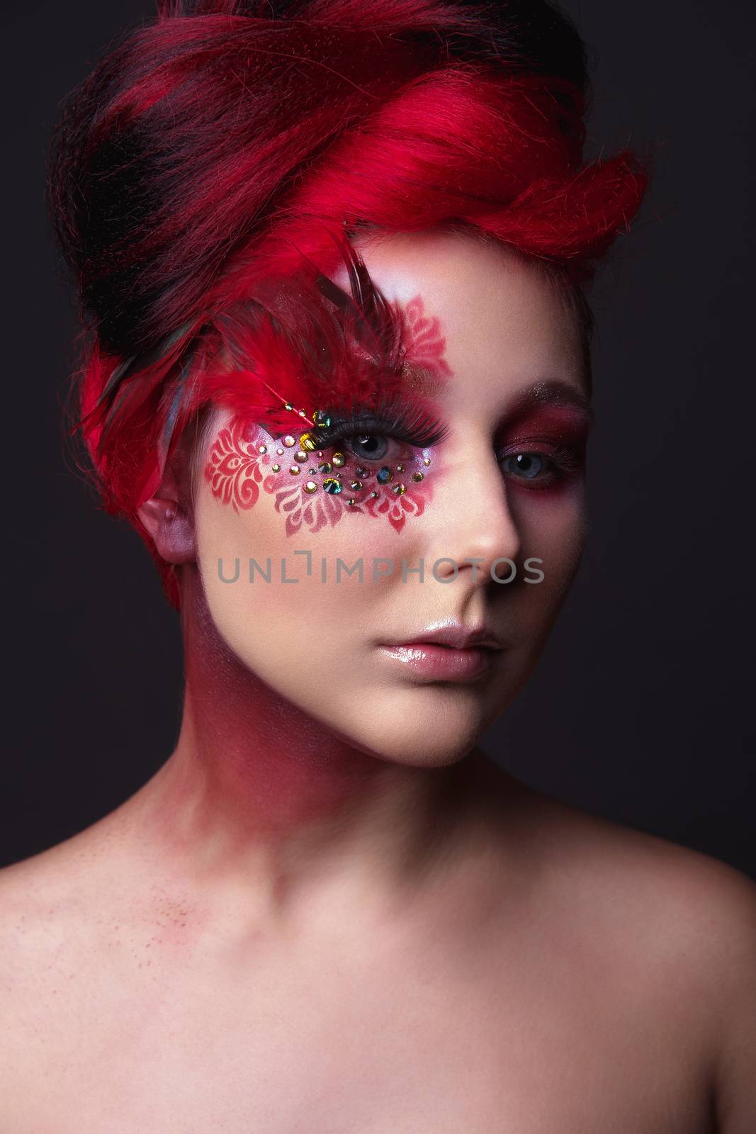 Portrait of a beauty young  girl with red hair.  Creative ingenious makeup with feathers, rhinestones and large eyelashes