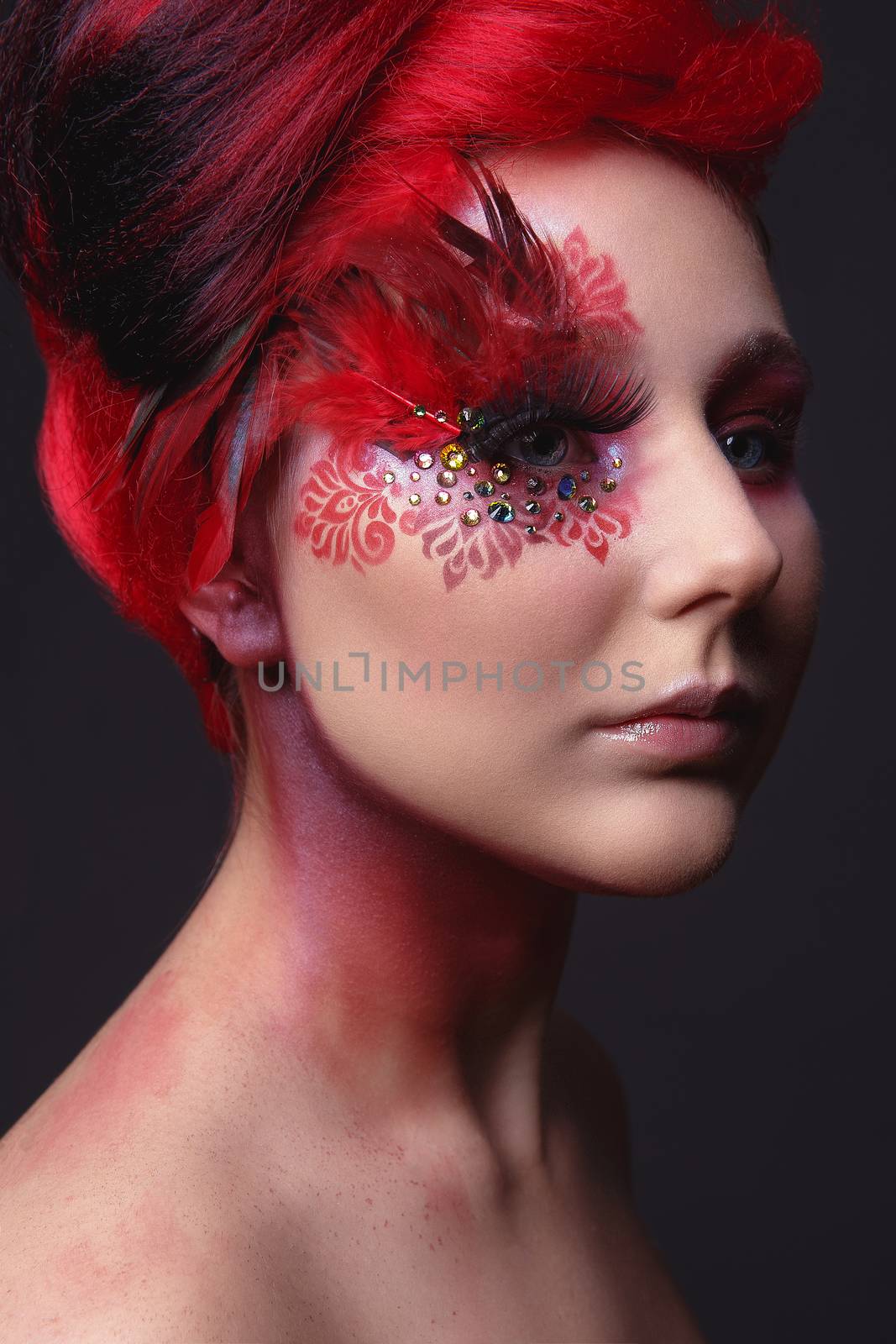 Portrait of a beauty young  girl with red hair.  Creative ingenious makeup with feathers, rhinestones and large eyelashes