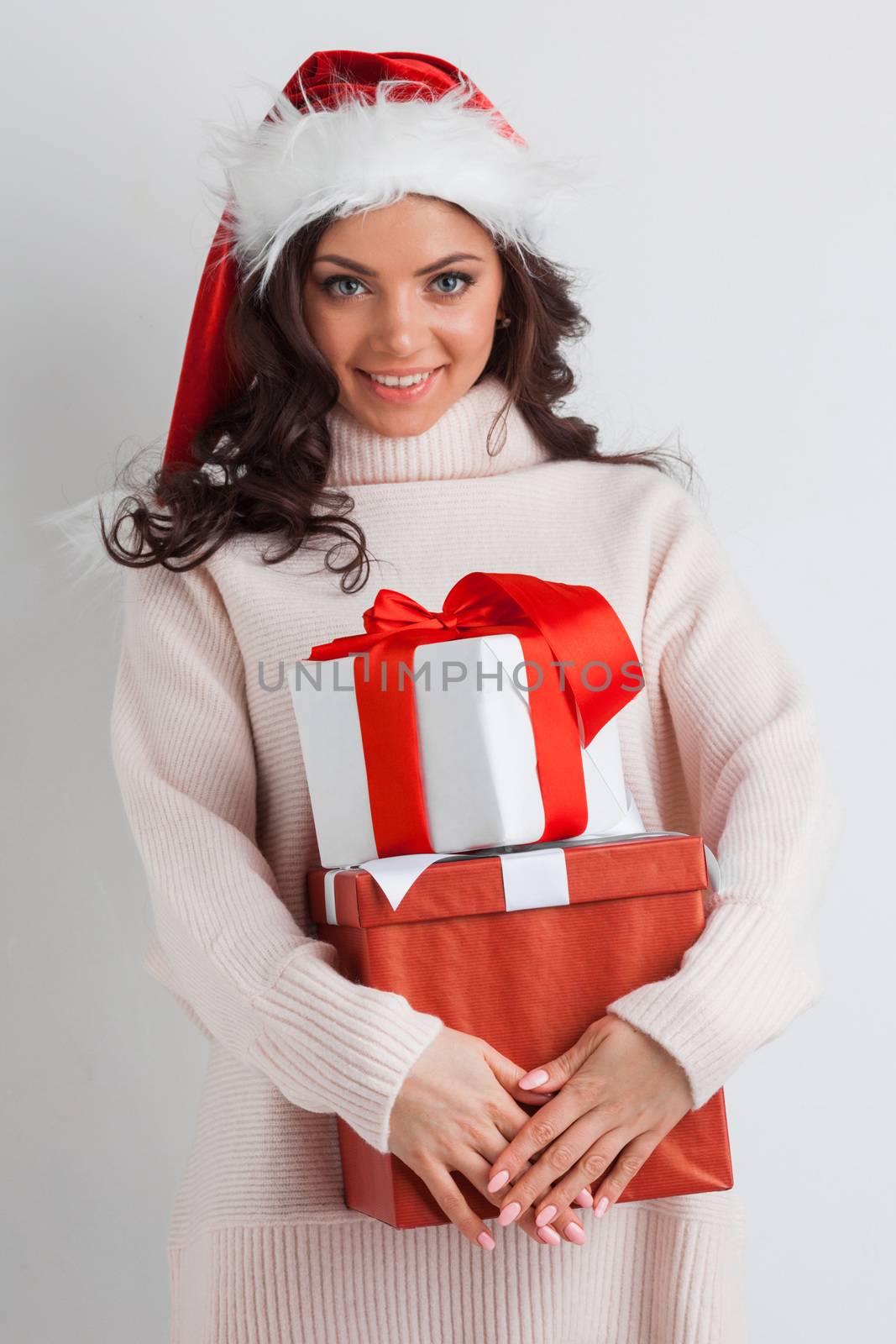 Young woman in Santa hat hug her Christmas gifts