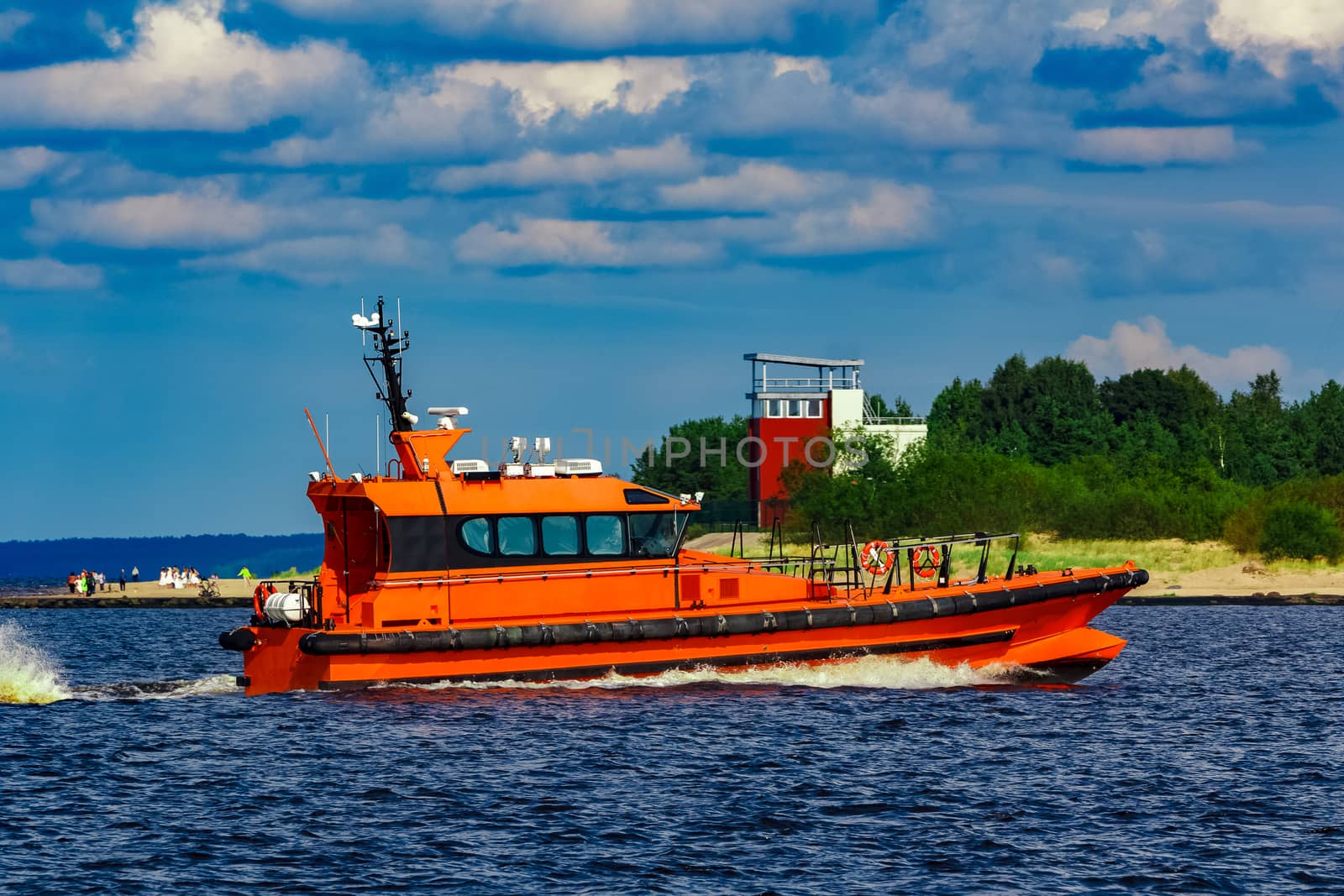 Orange pilot boat moving by the river in Europe. Rescue service