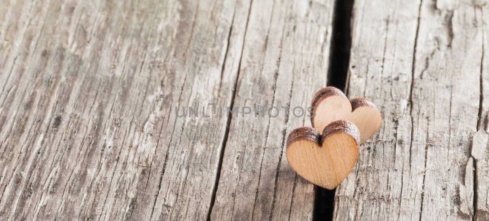 Two small wooden hearts on old cracked wood background