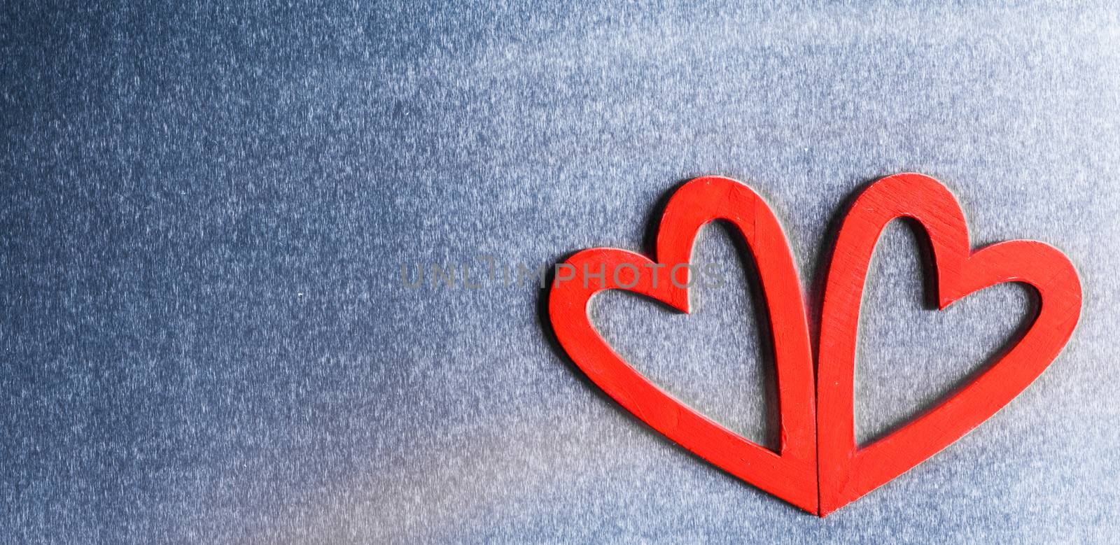 Two red wooden hearts on metal background with copy space