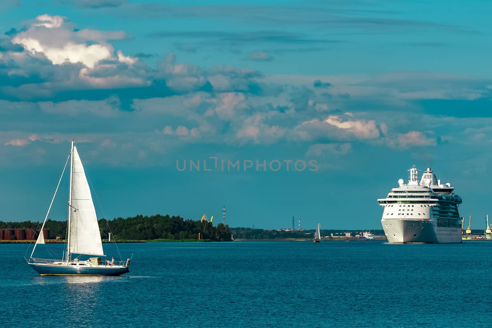 Blue sailboat traveling against the cruise liner in Riga