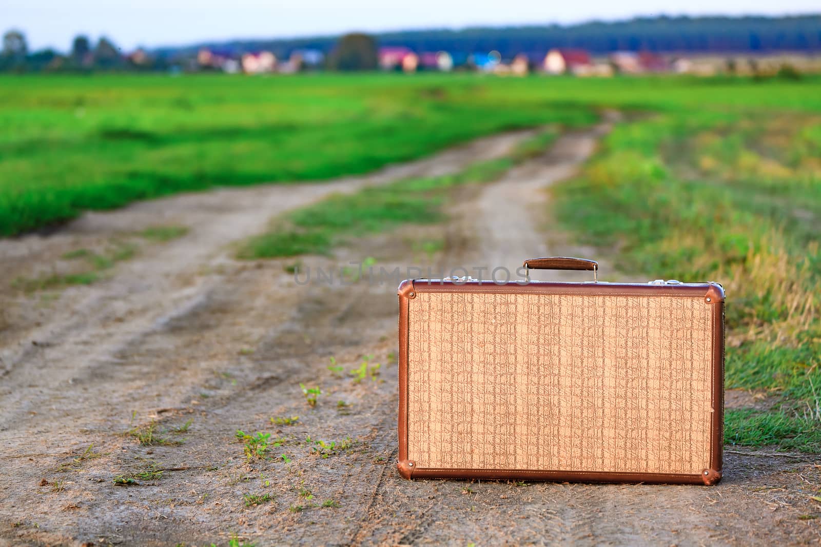 Retro styled old suitcase on a countryside road by Nobilior