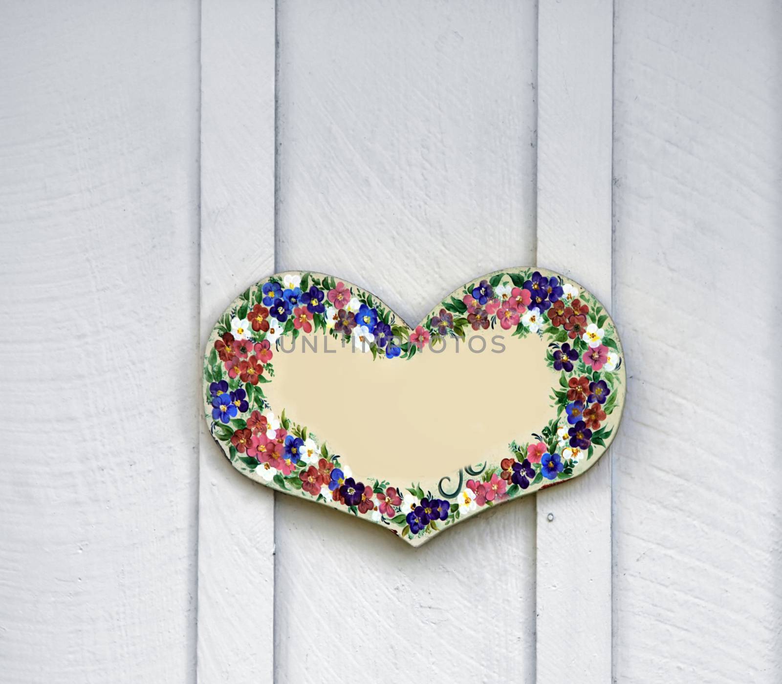 Wooden heart with painted flowers, like decoration on a wooden door