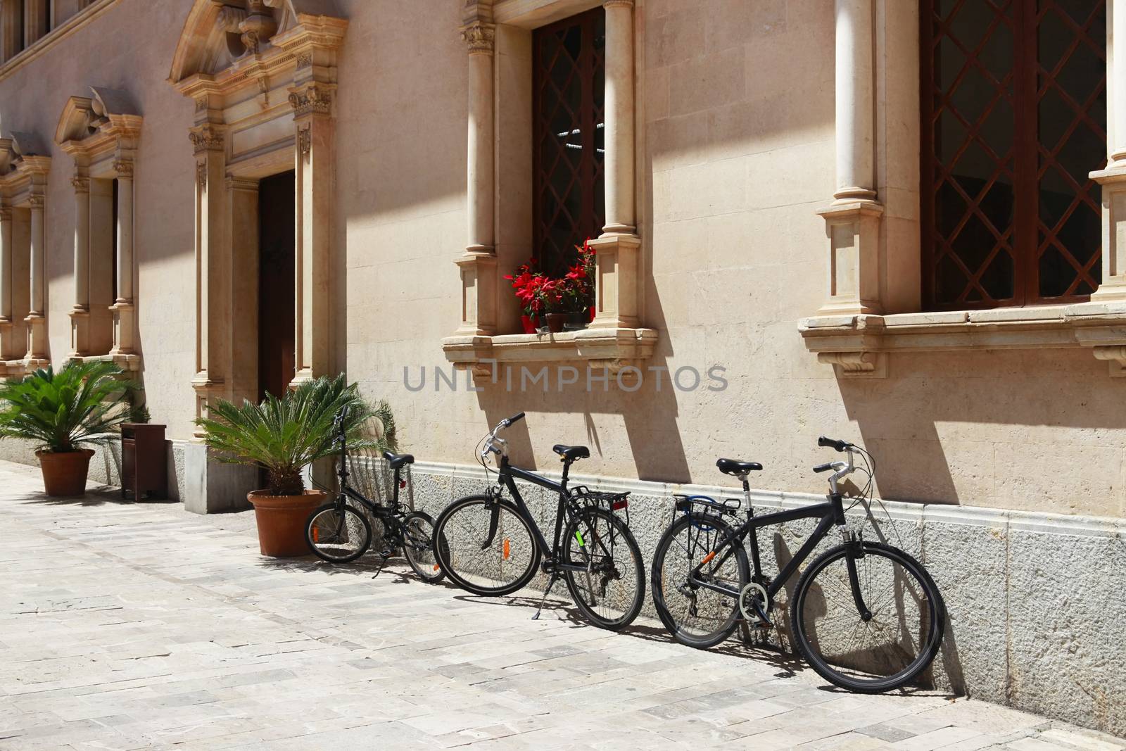 Parked bicycles near a beautiful building in Alcudia, Spain