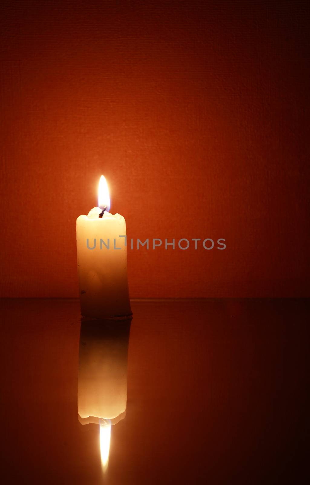 One lighting candle with reflection against dark background