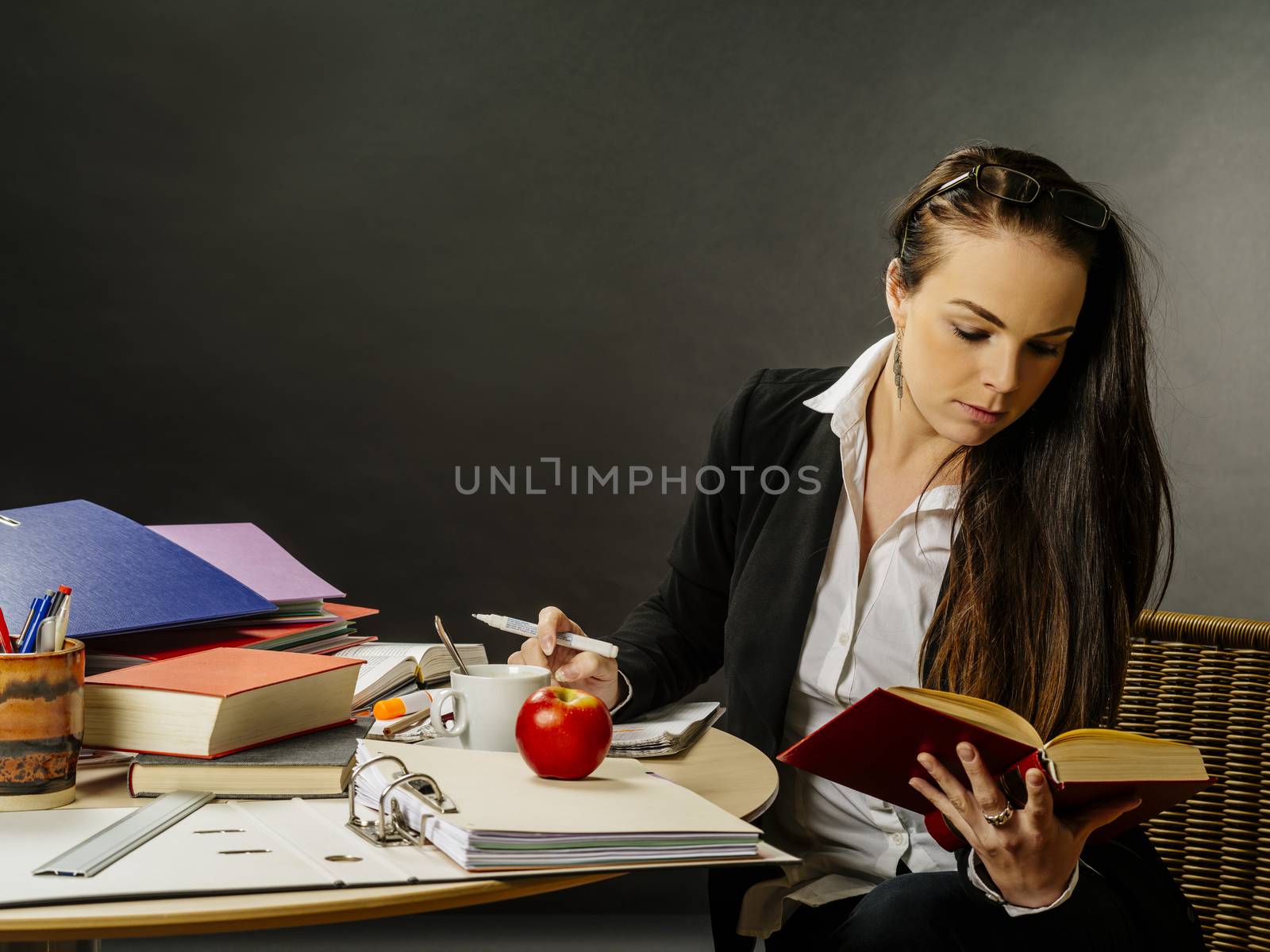 Beautiful teacher sitting at her desk reading by sumners