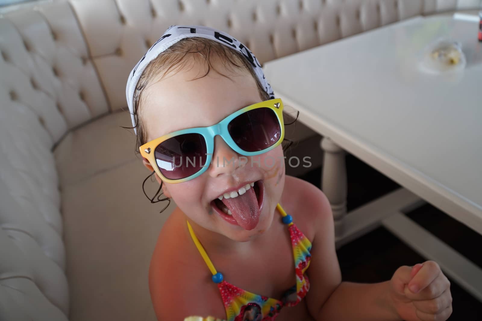 little girl tongue out. Mouth smeared with colored candy. Mood cheerful