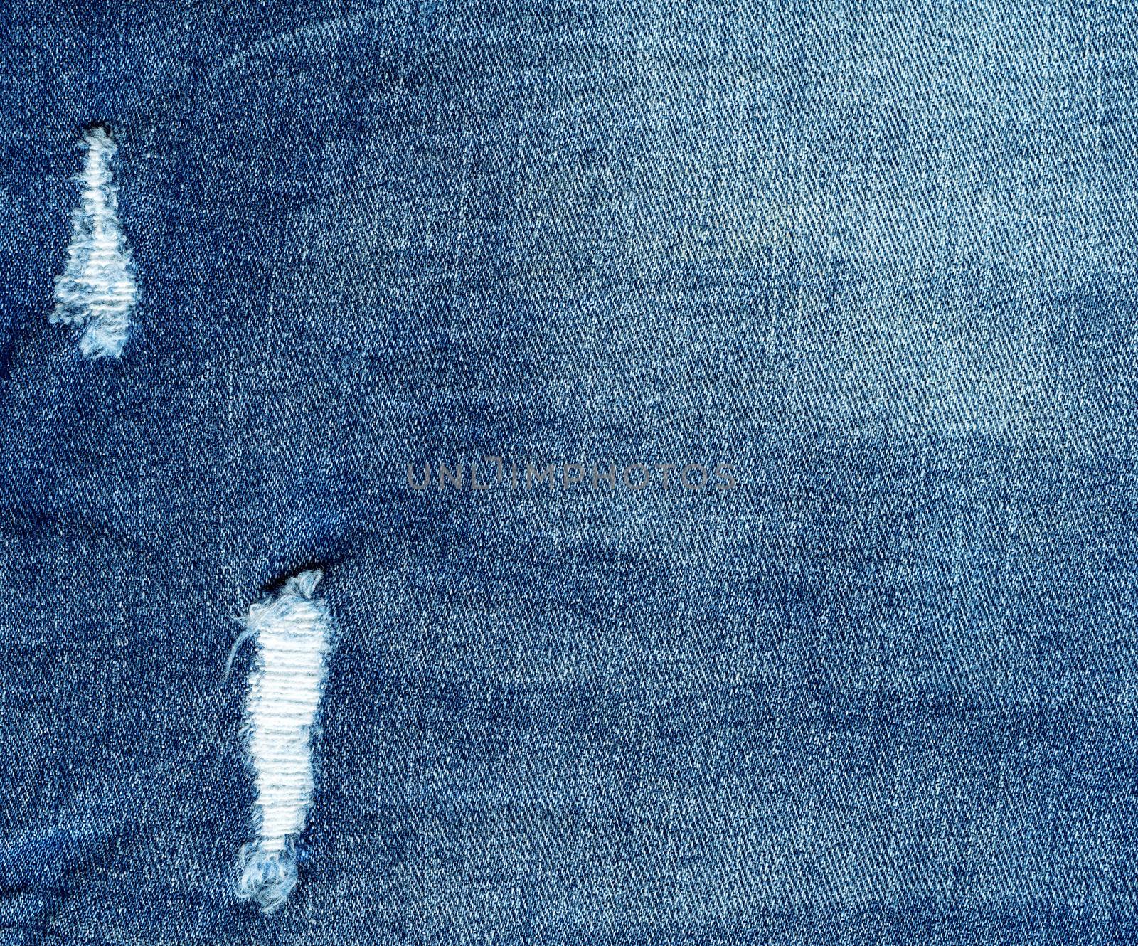 Denim texture, light torn jeans. Modern design of the old wearing ripped jeans
