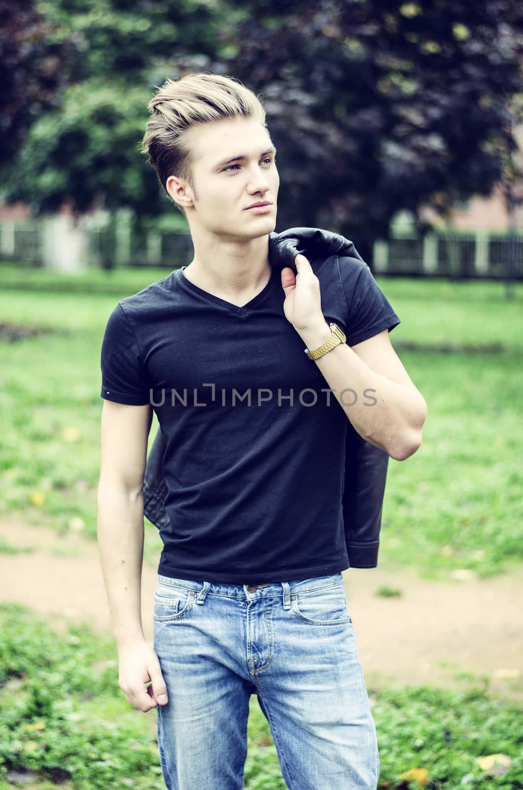 Attractive young man standing in city environment, with rucksack on one shoulder