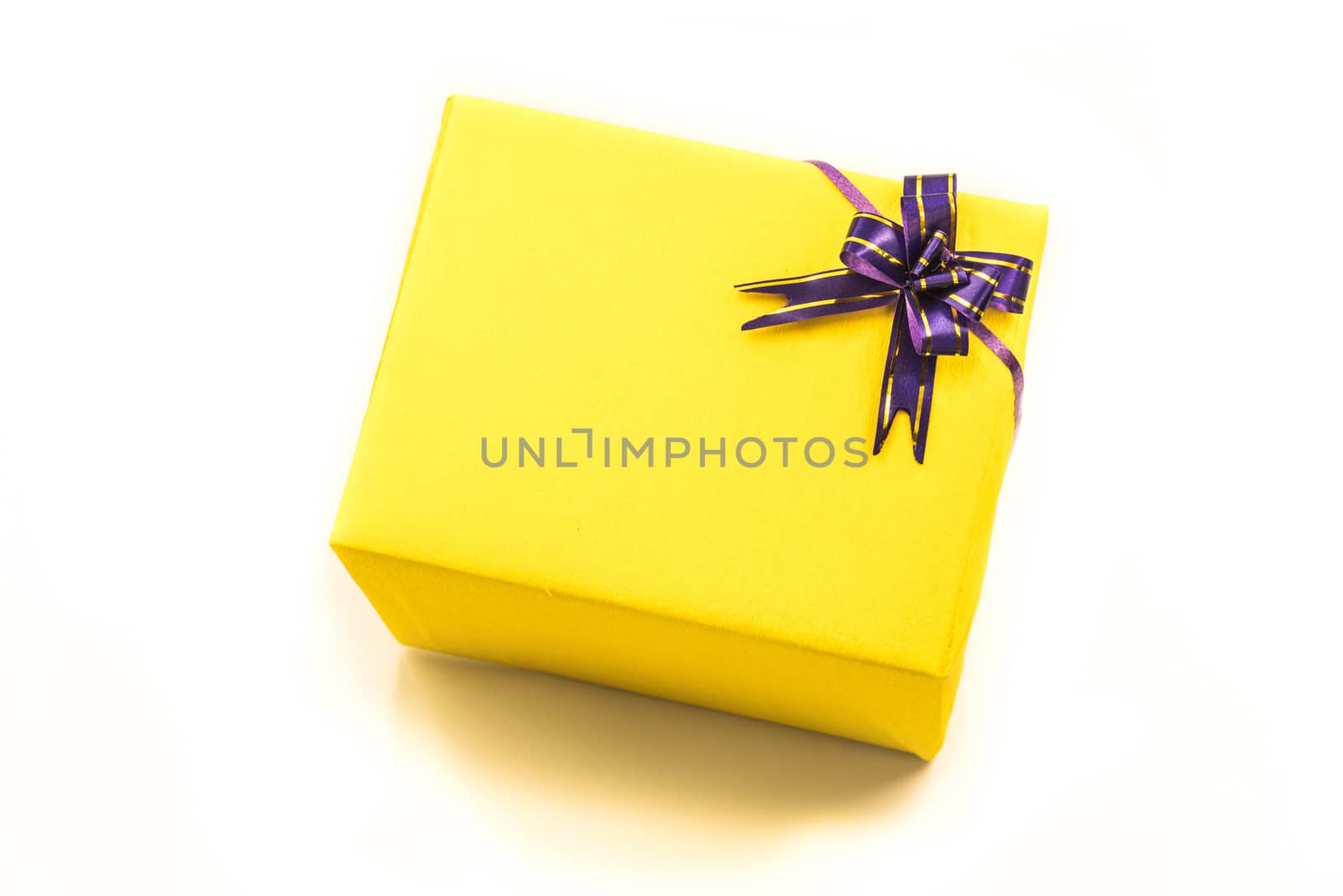 bright yellow hand made gift box with nice crepe wrapping and purple bow. Happy holidays.