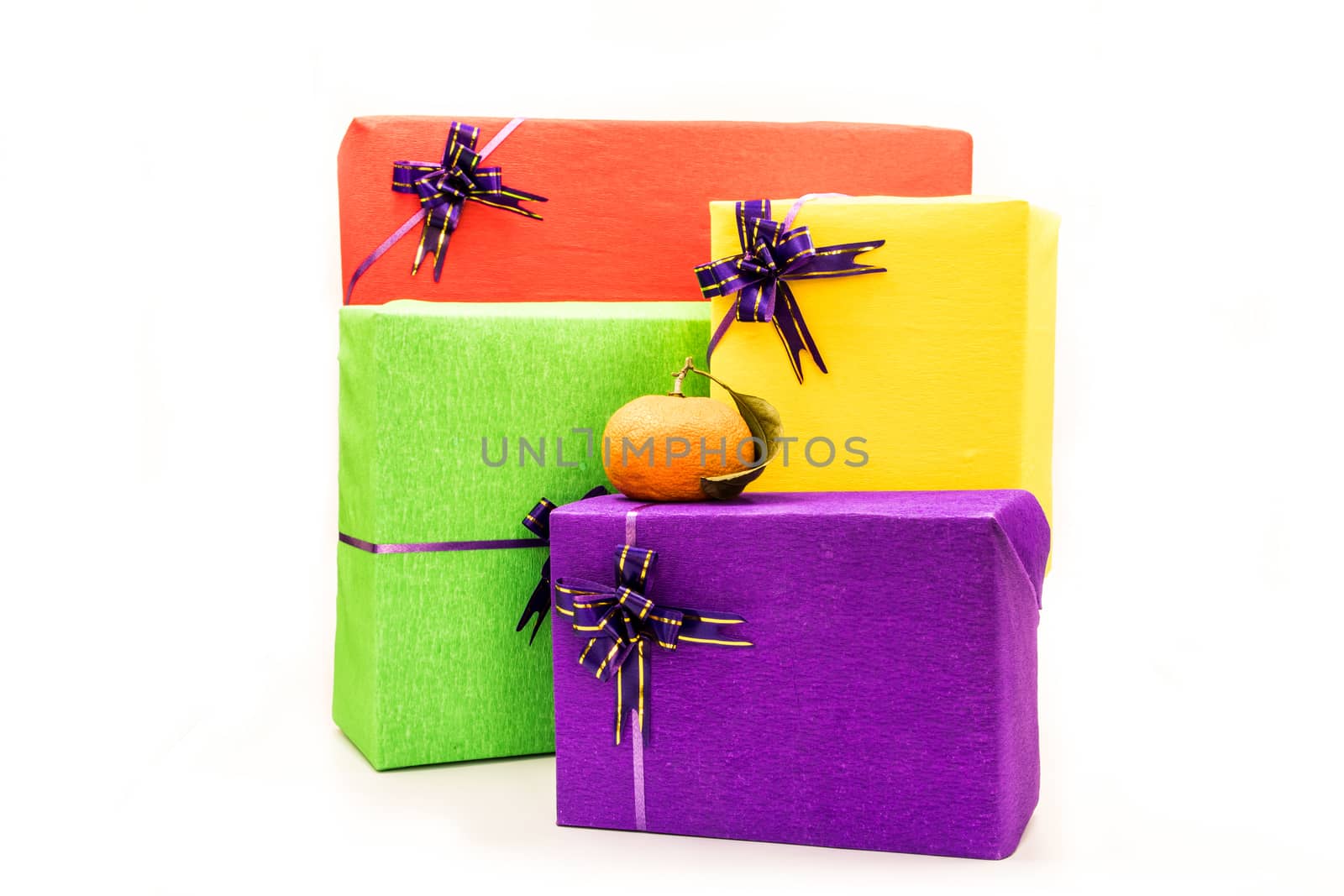 pile of colorful gift boxes wrapped in crepe paper with purple bows an orange on the top. Holiday presents concept