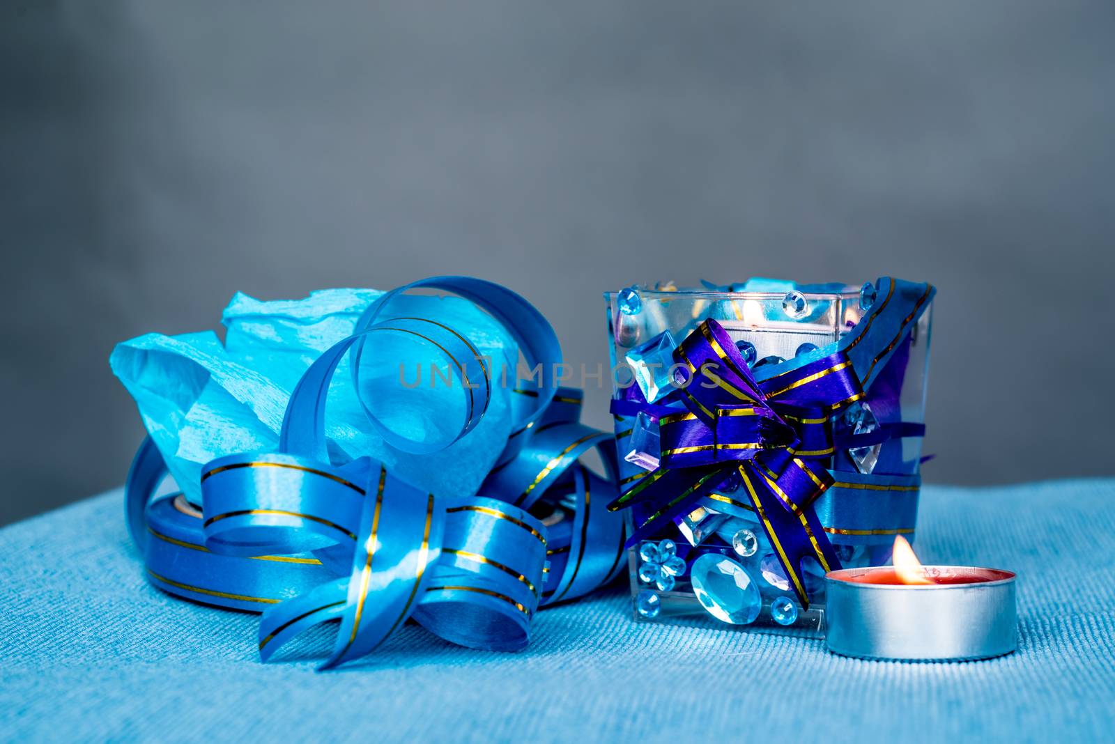 christmas craft composition on the blue tablecloth. candle with gems and blue ribbon by Desperada