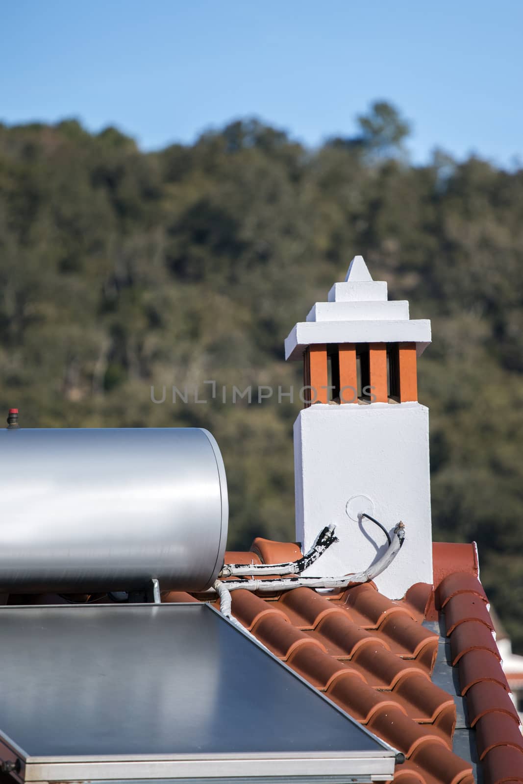 View of a solar panel on red tile rooftop in Europe.