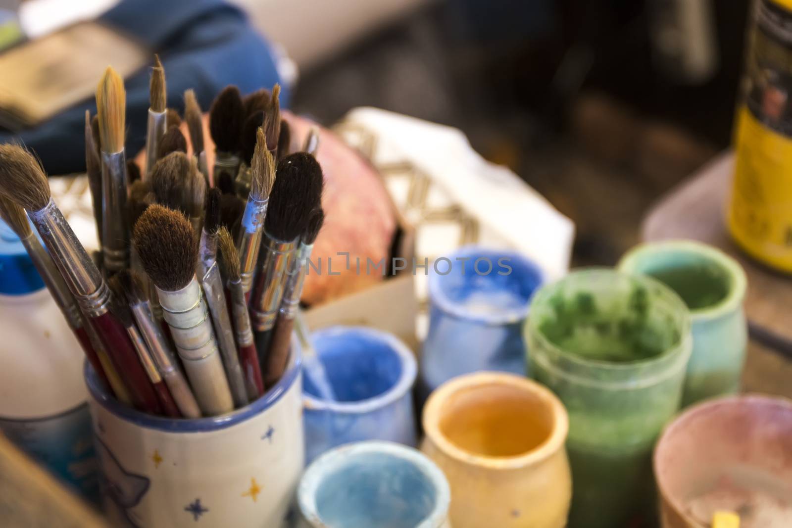 Artist table with used painting buckets and brushes.