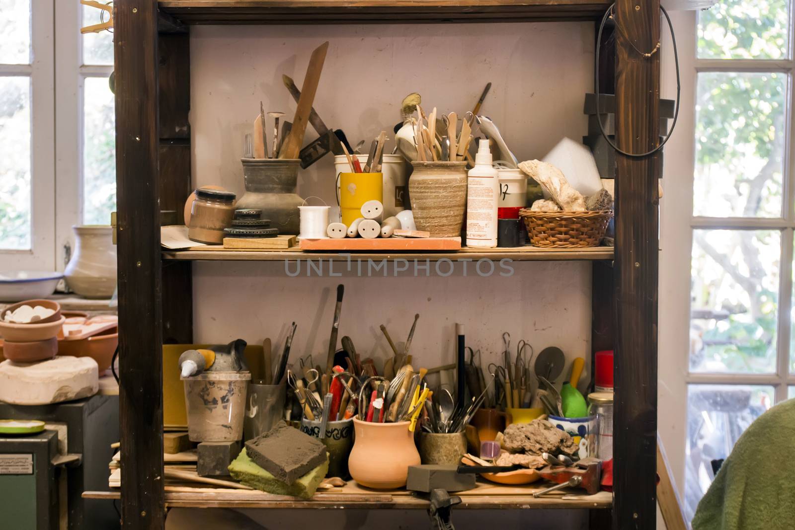 Artist studio shelf with used painting tools and brushes.