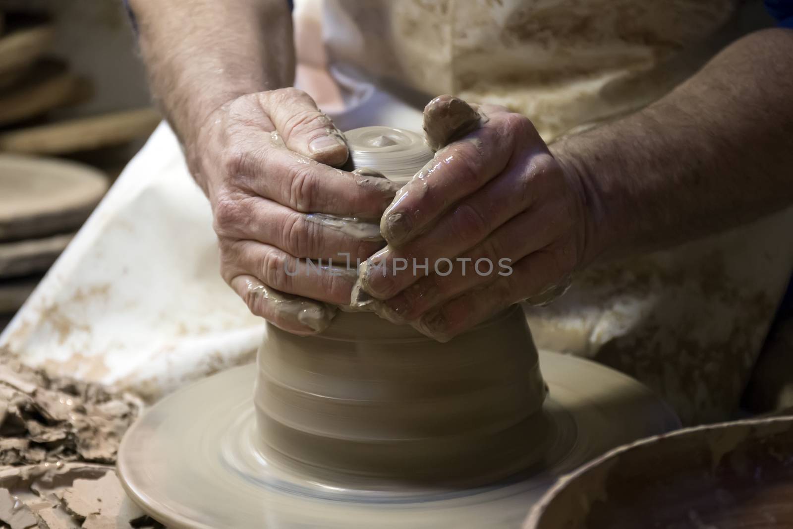 Close up view of the hands of ceramic artist making a piece from clay.