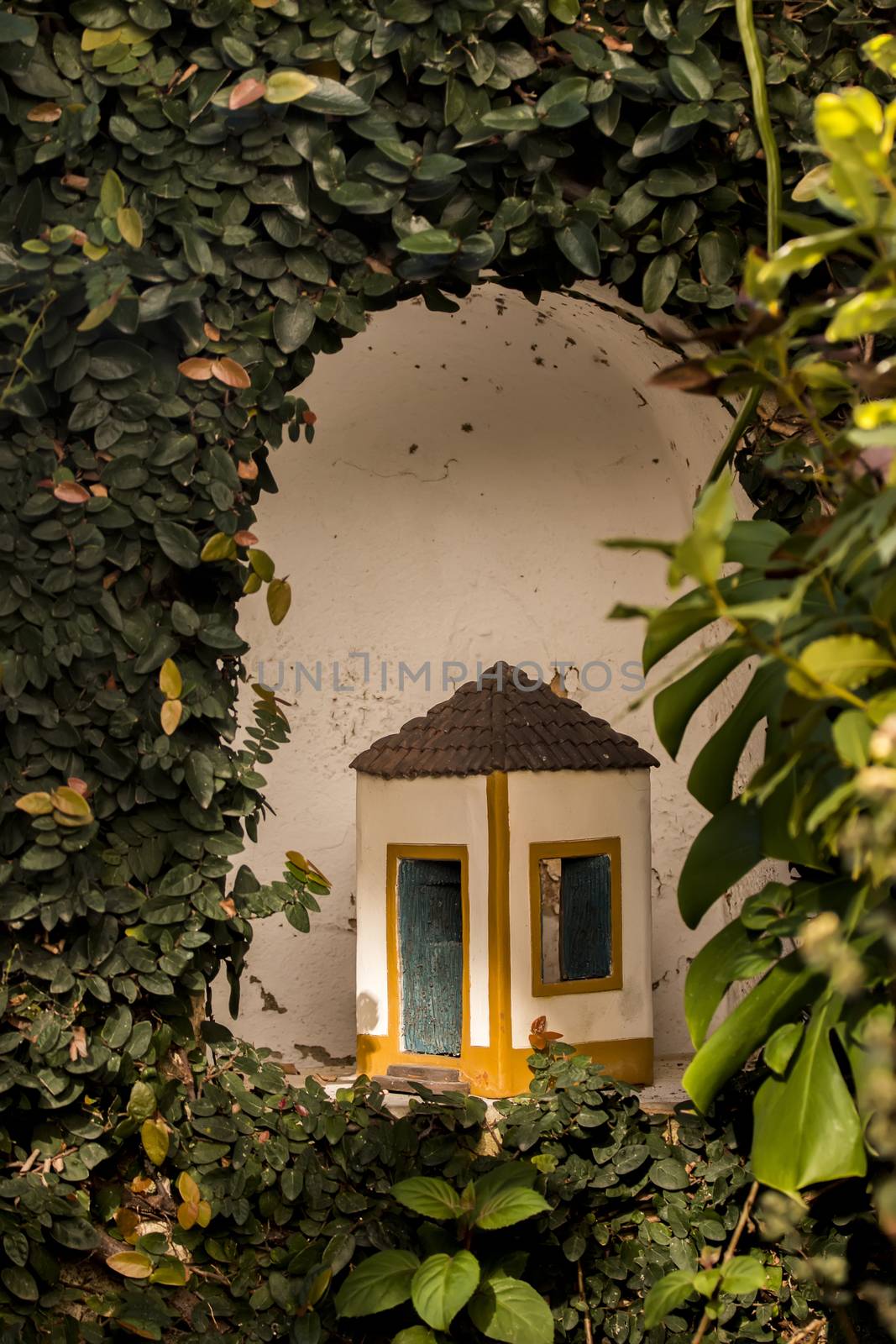 Curious ceramic tiny house in Portuguese style in a garden.