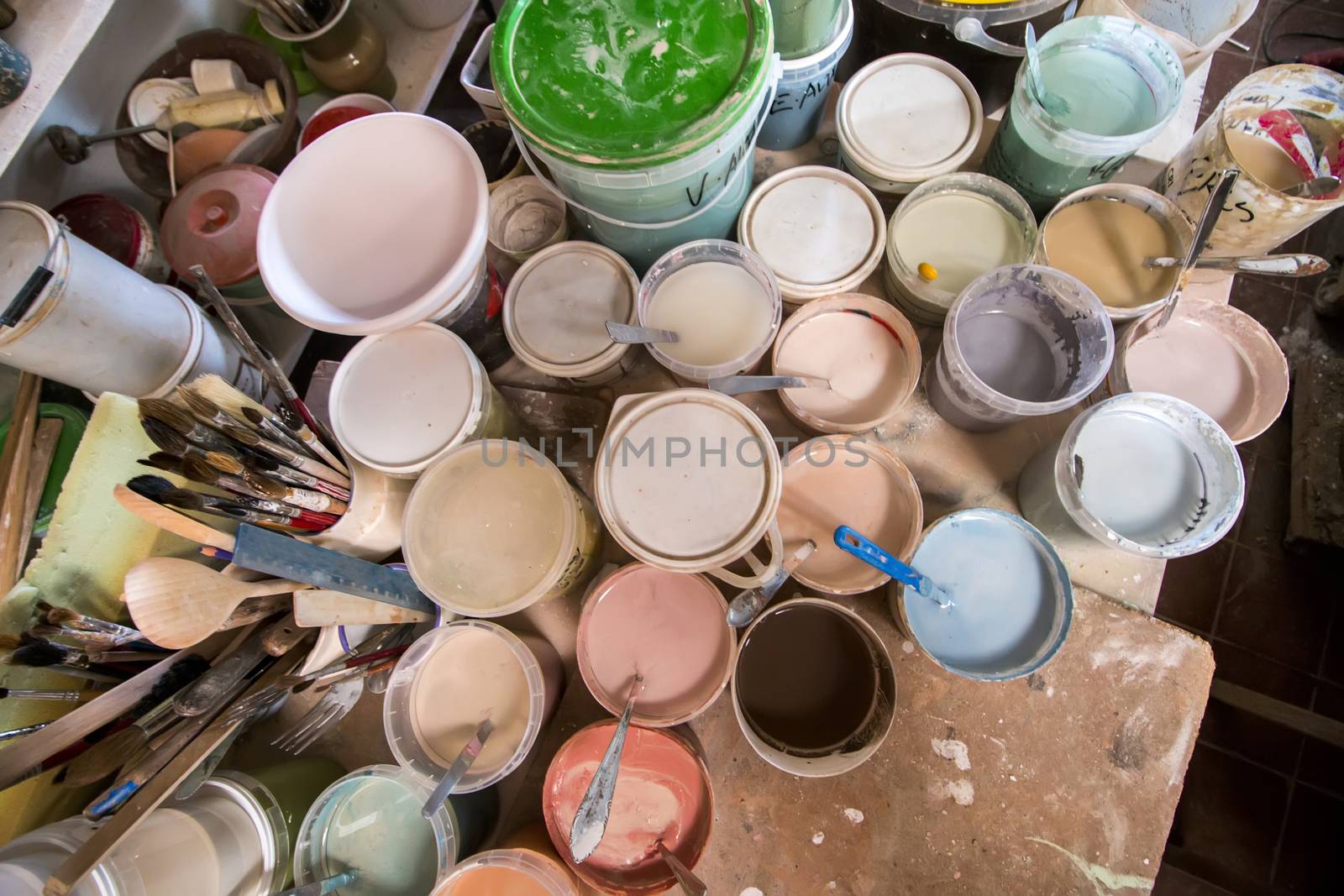 Artist studio with used painting buckets and brushes.