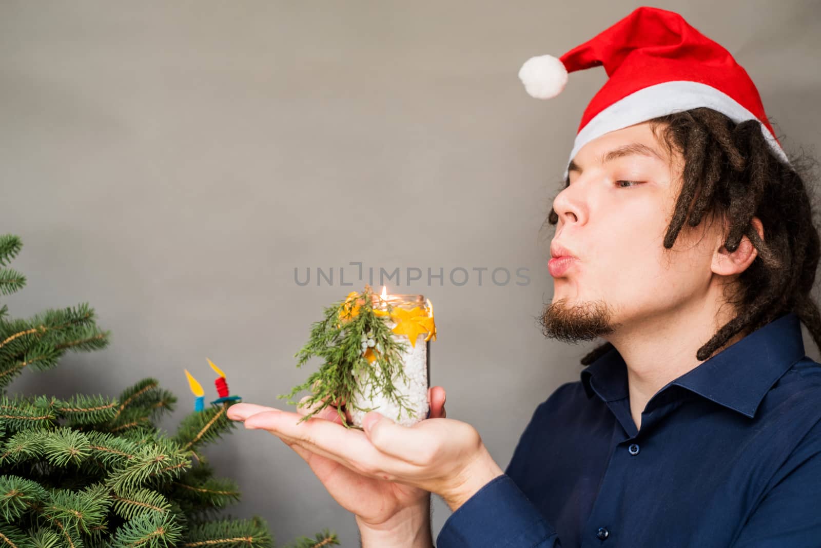 caucasian man with afro hairstyle and santa hat holding a hand made candle craft by Desperada