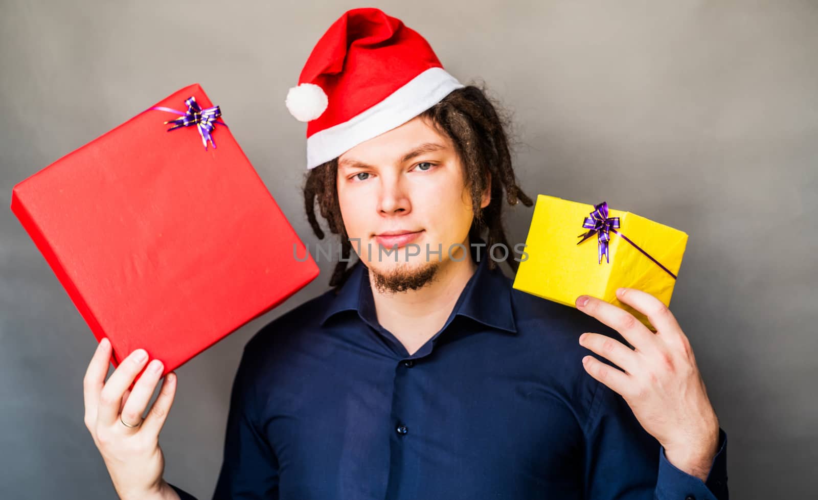 Young man in santa hat holding two christmas gifts by Desperada