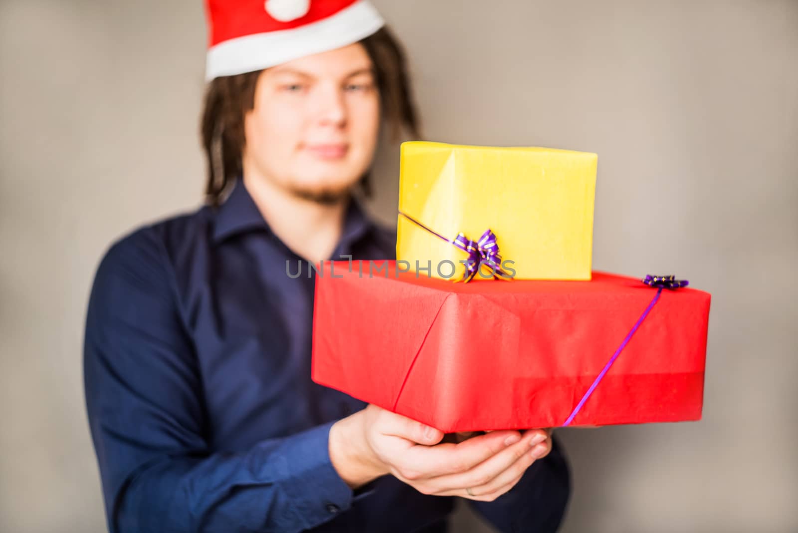 smiling young caucasian man with afro hair holding christmas presents. christmas concept