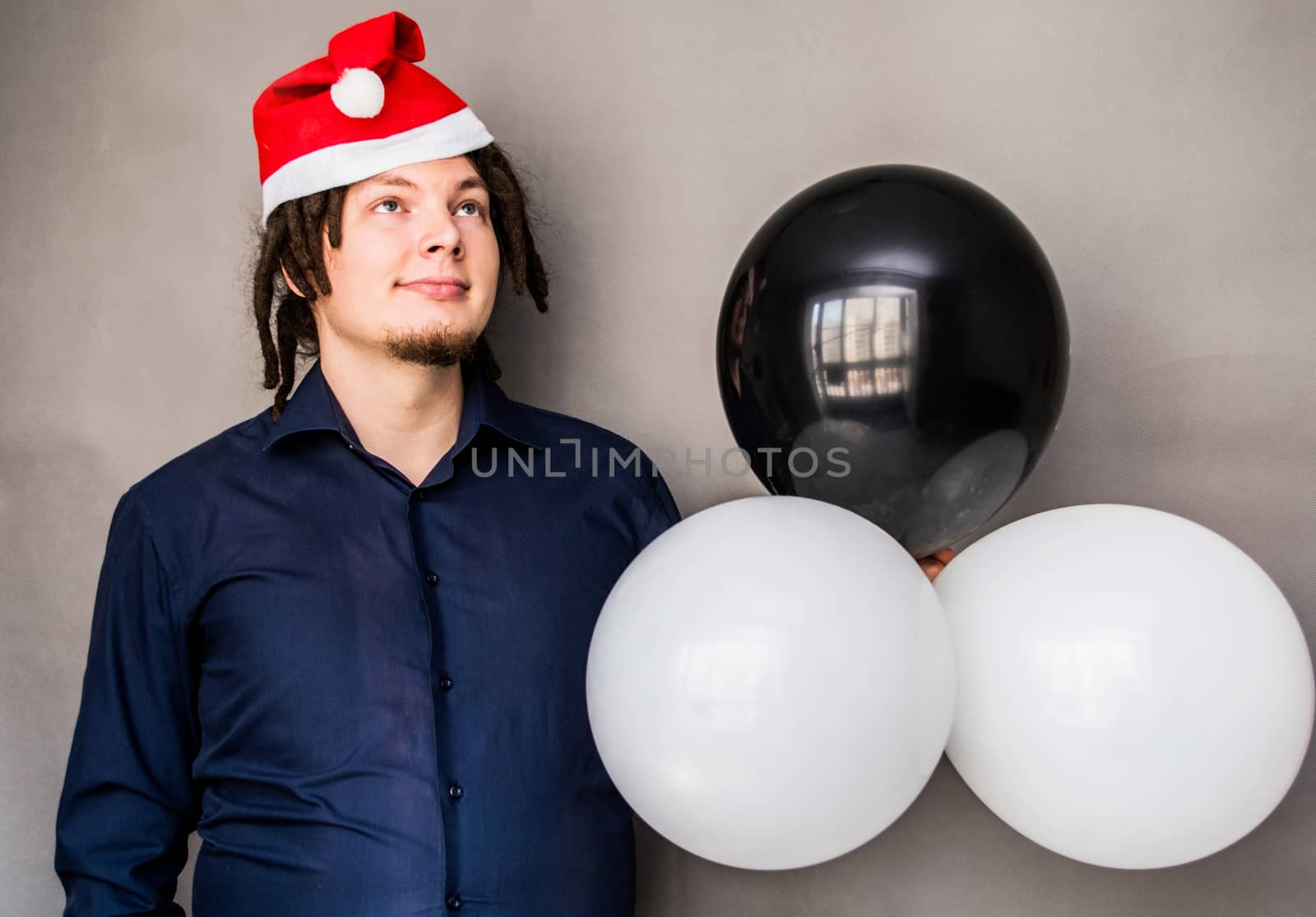 smiling young caucasian man with afro hair holding balloons. christmas concept