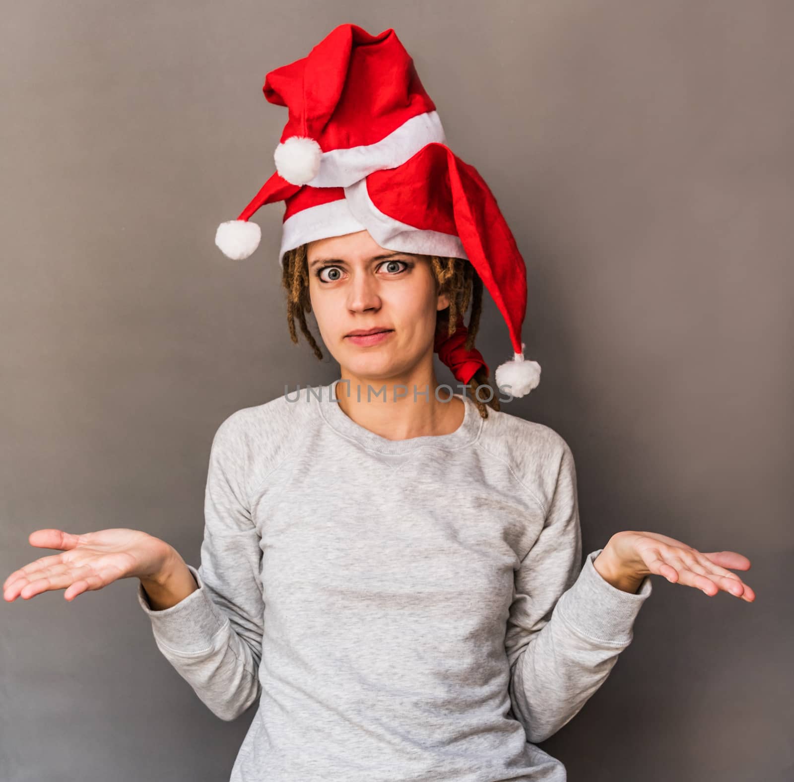 surprised young caucasian woman with tree christmas hats shrugging her shoulders