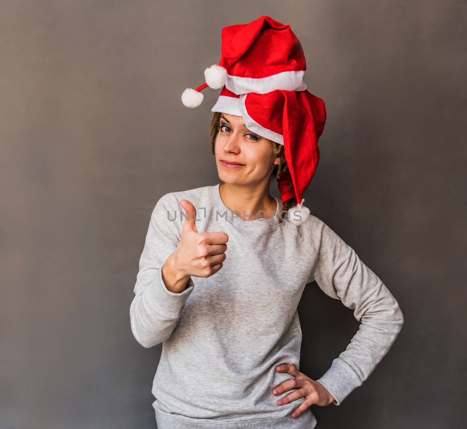 funny happy young caucasian woman with tree christmas hats showing thumb up