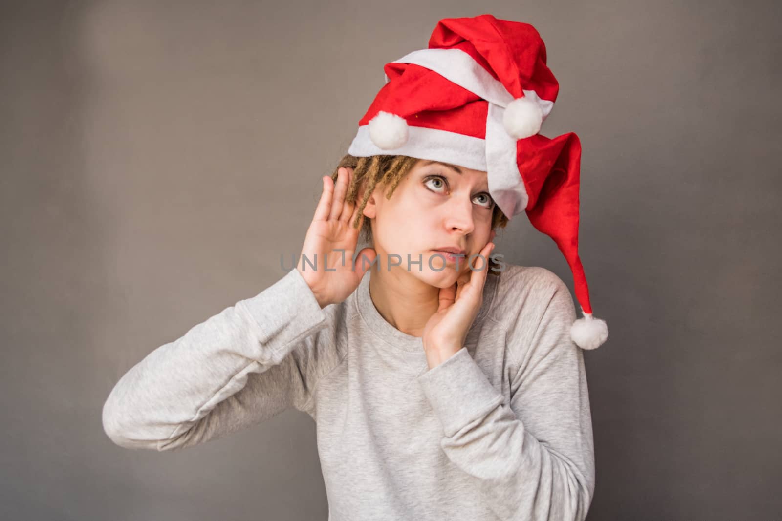 emotions. caucasian woman in santa hats listening holding her hand next to the ear