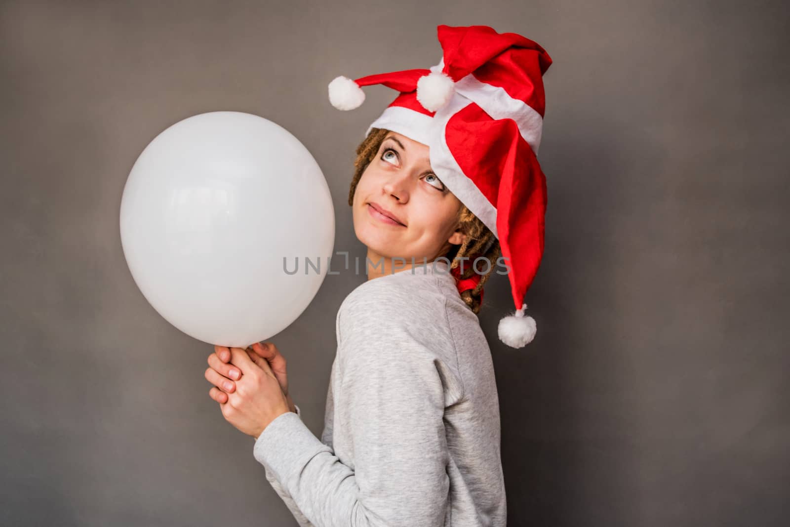 christmas concept. young caucasian woman with tree santa hats holding a balloon dreaming and smiling