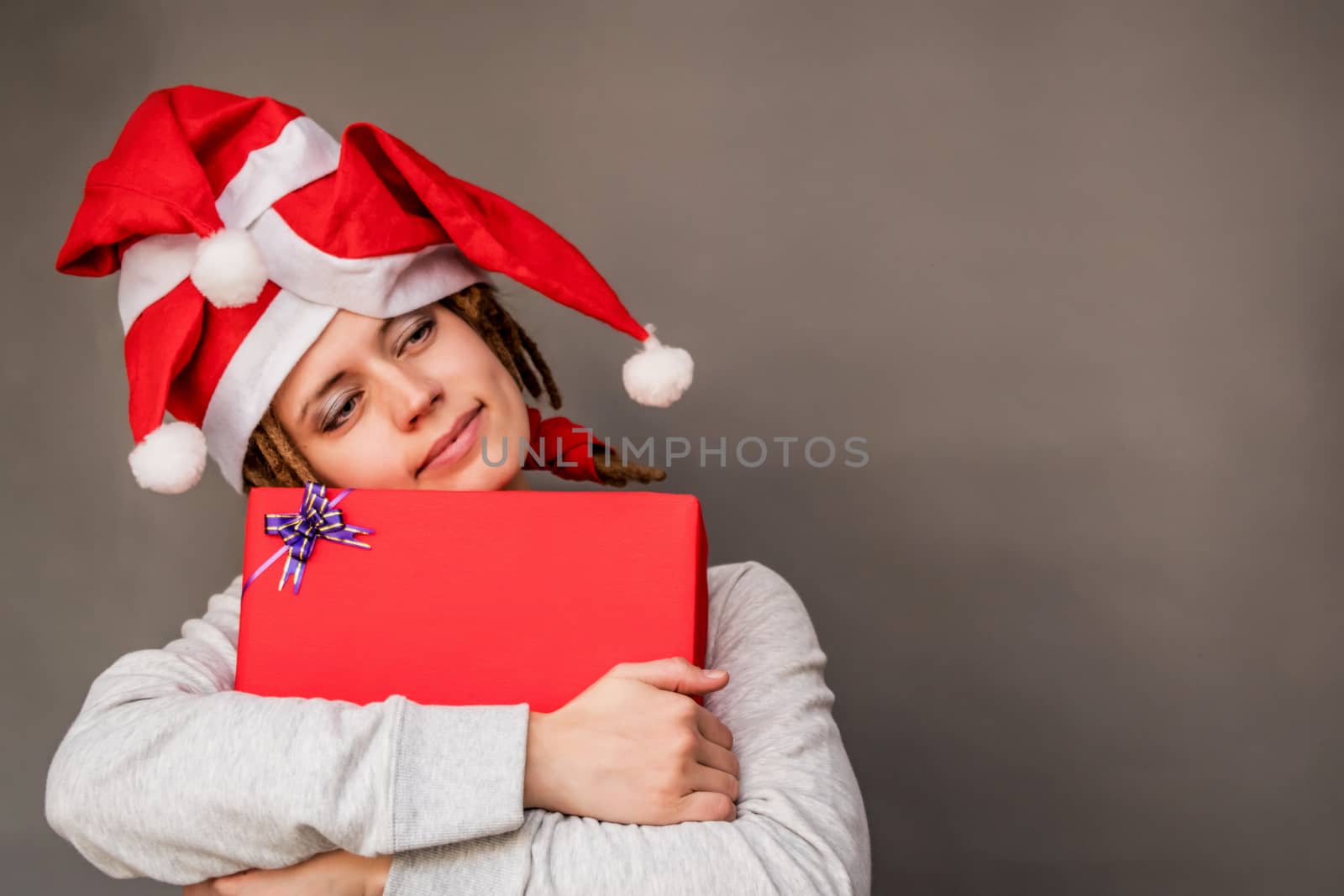 funny happy young caucasian woman with tree christmas hats with a gift dreaming
