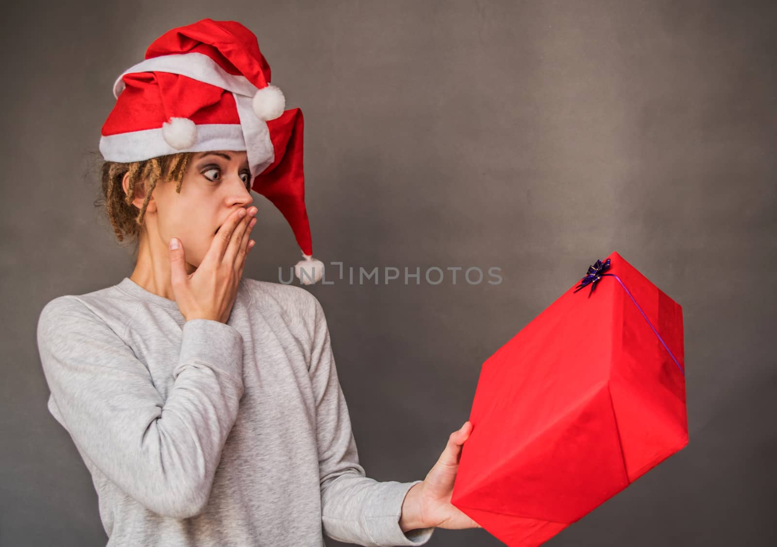 surprised woman with afro hair in tree santa hats looking at the present by Desperada