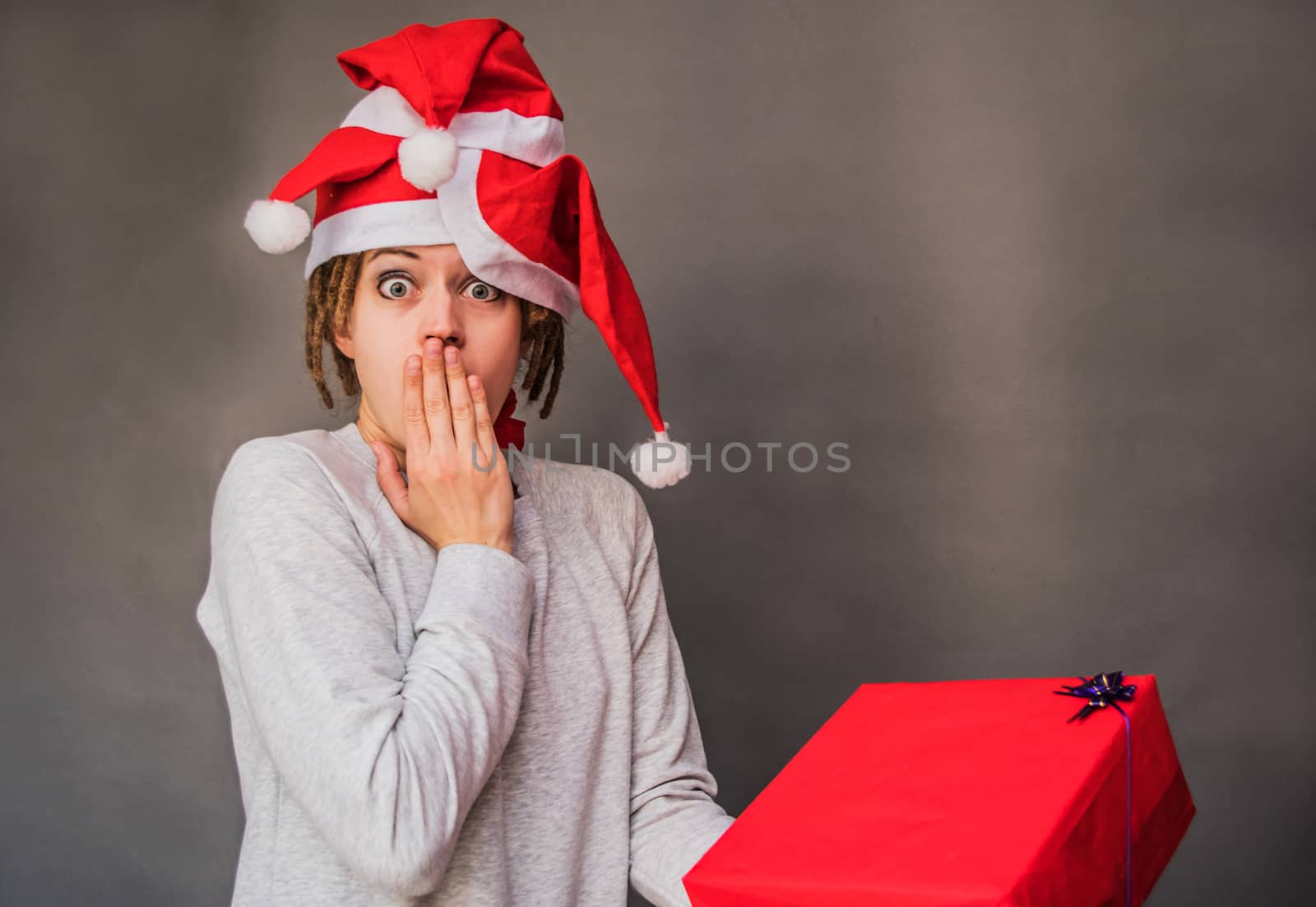 surprised woman with afro hair in tree santa hats looking at the present by Desperada