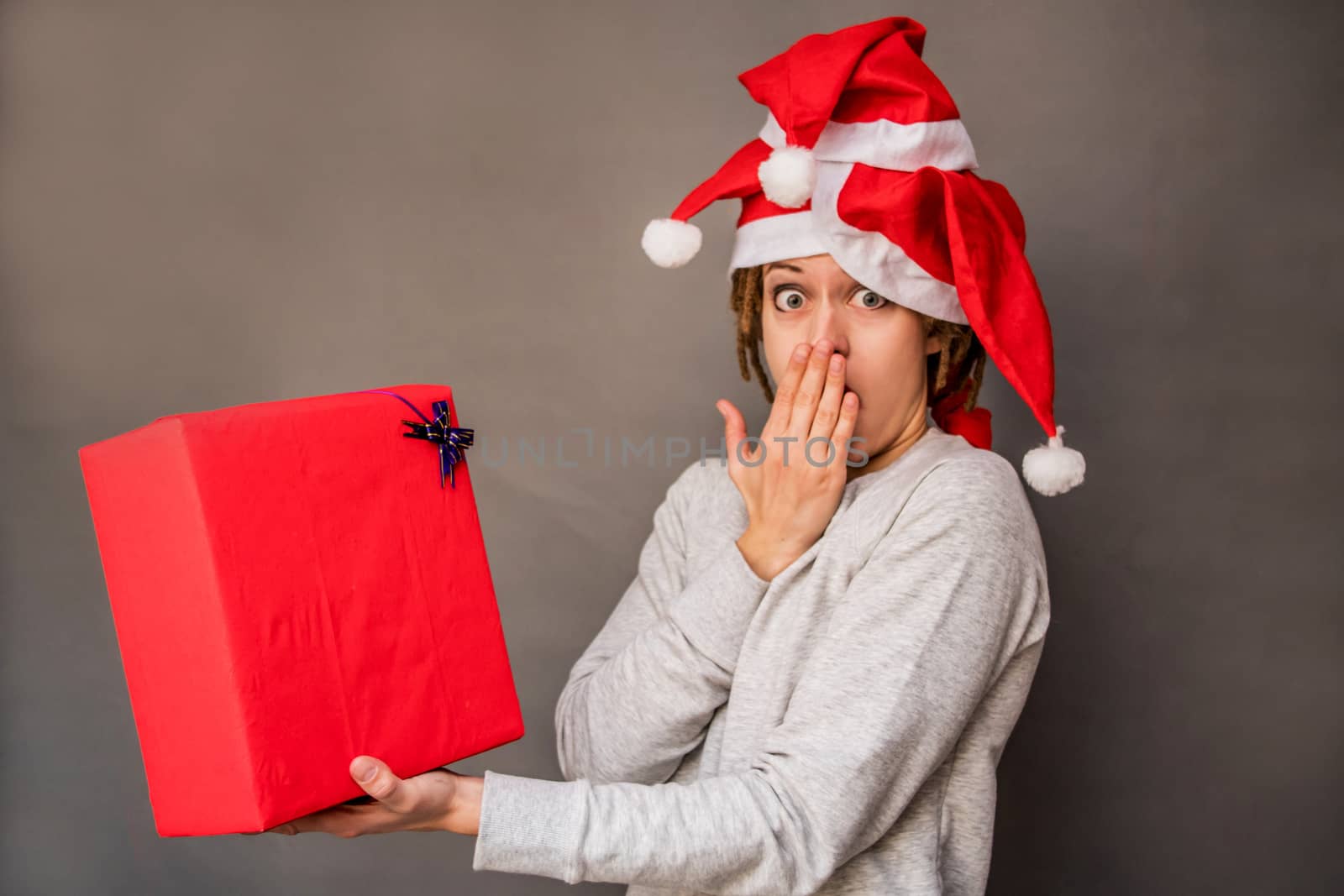 surprised woman with afro hair in tree santa hats looking at the present by Desperada