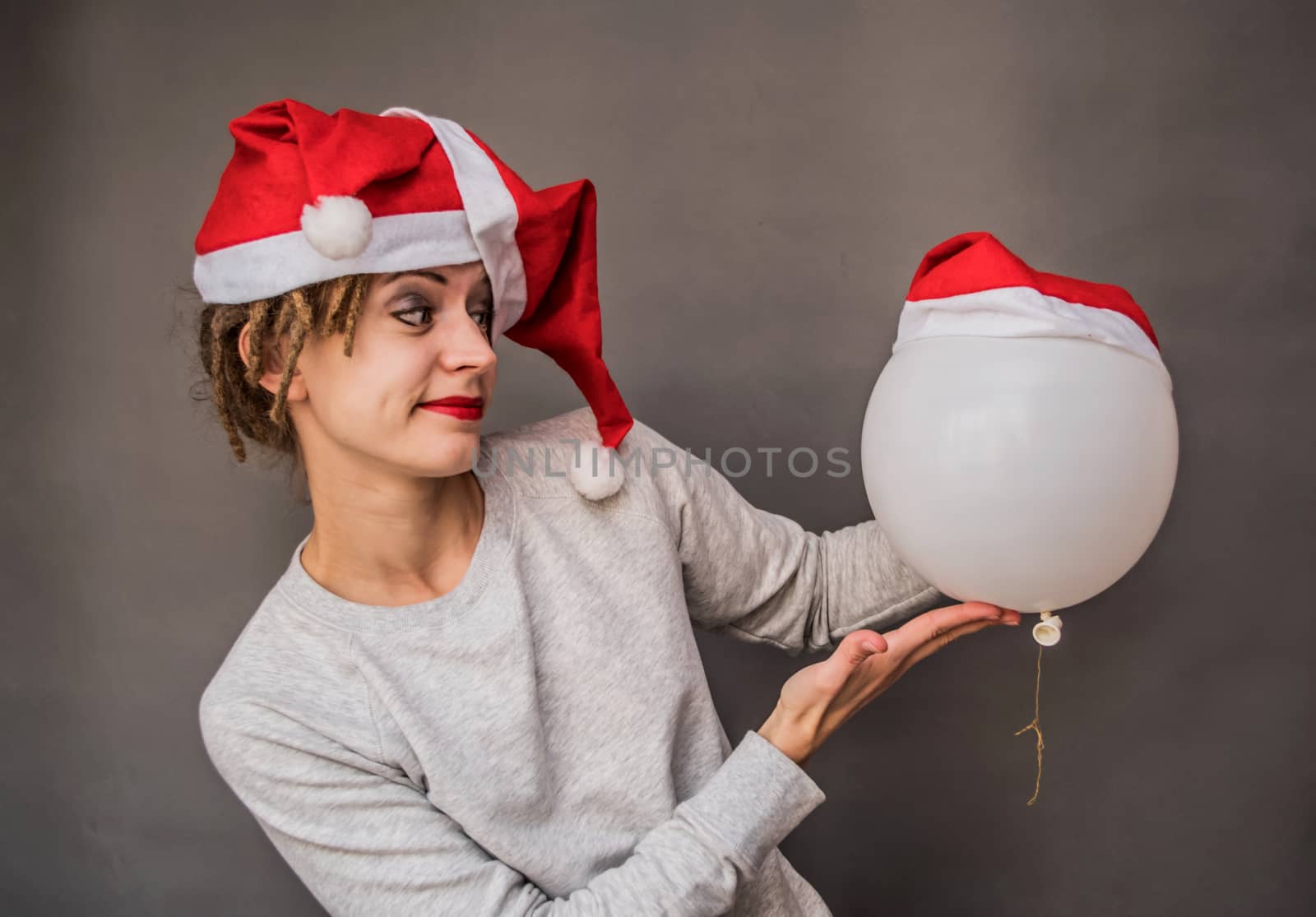 christmas concept. cheerful funny caucasian woman in santa hat playing with white balloon