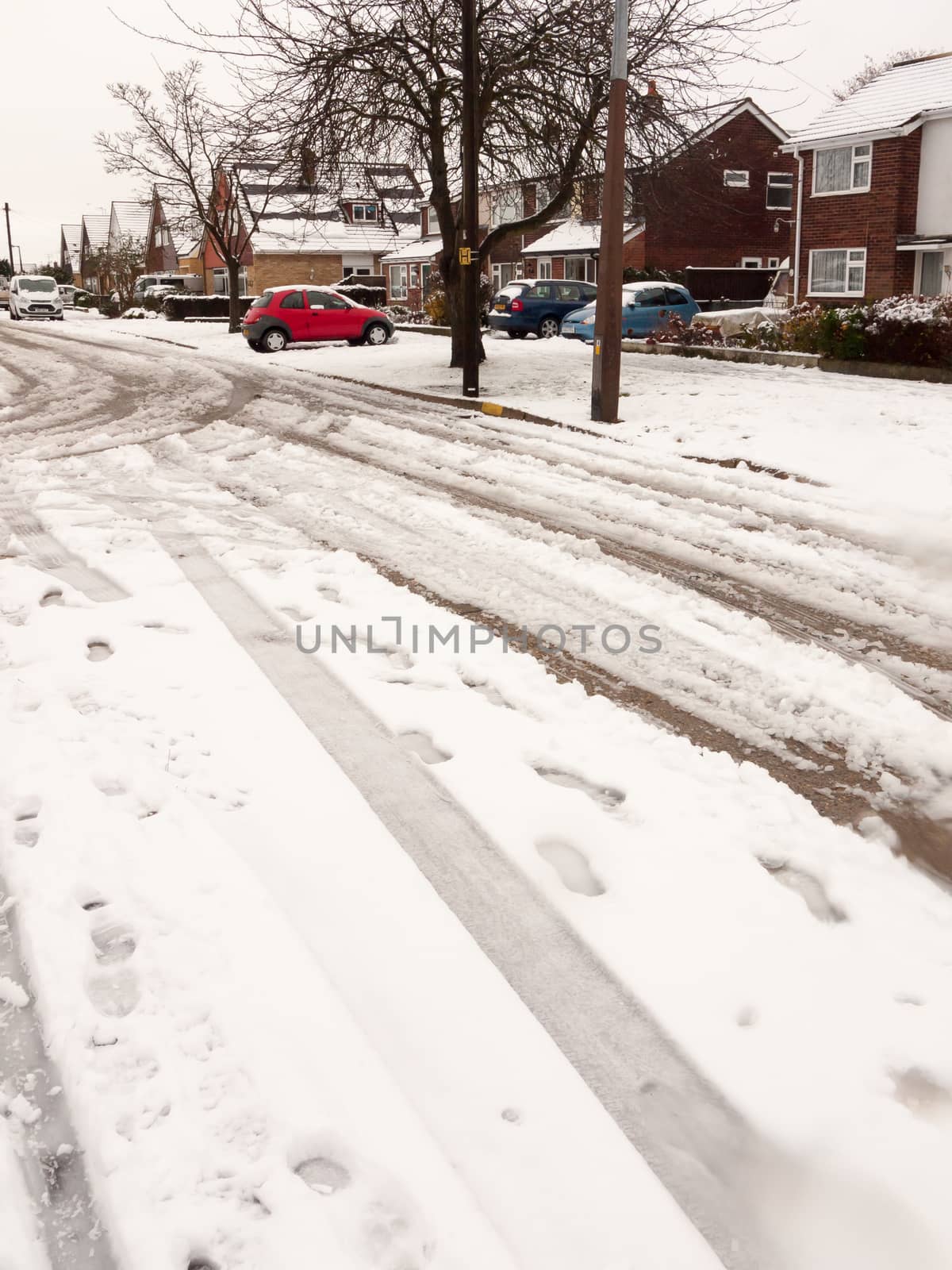 snow covered street road with tire tracks leading through villag by callumrc